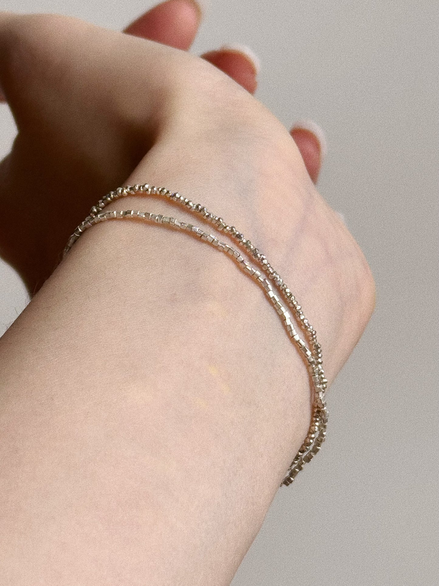 Close up on wrist showing the sparkling handmade faceted silver beads of the double layer bracelet, highlighting the dainty chain texture.