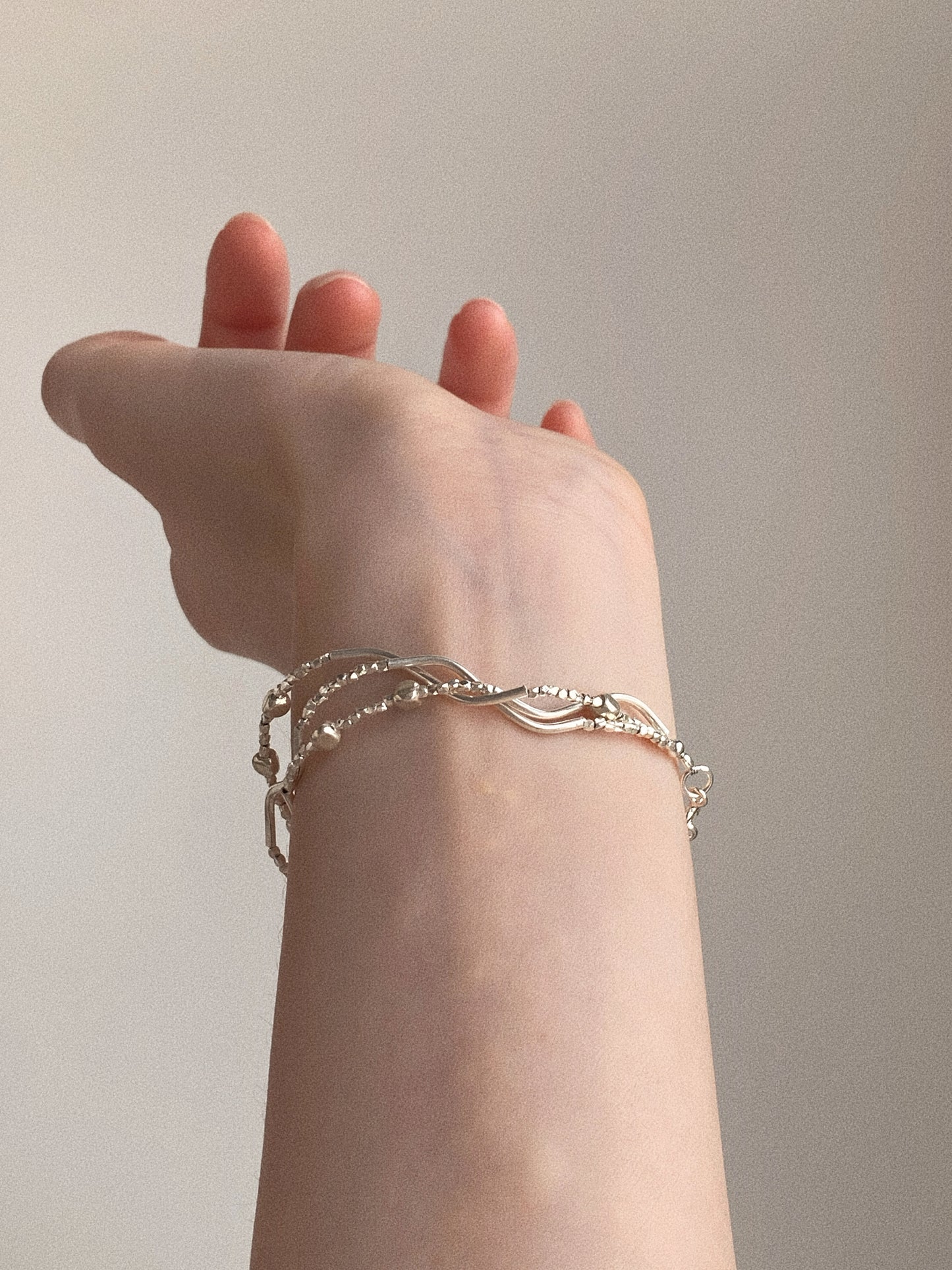 Multi-strand sterling silver bracelet styled on model with raised wrist showing daily wear silhouette