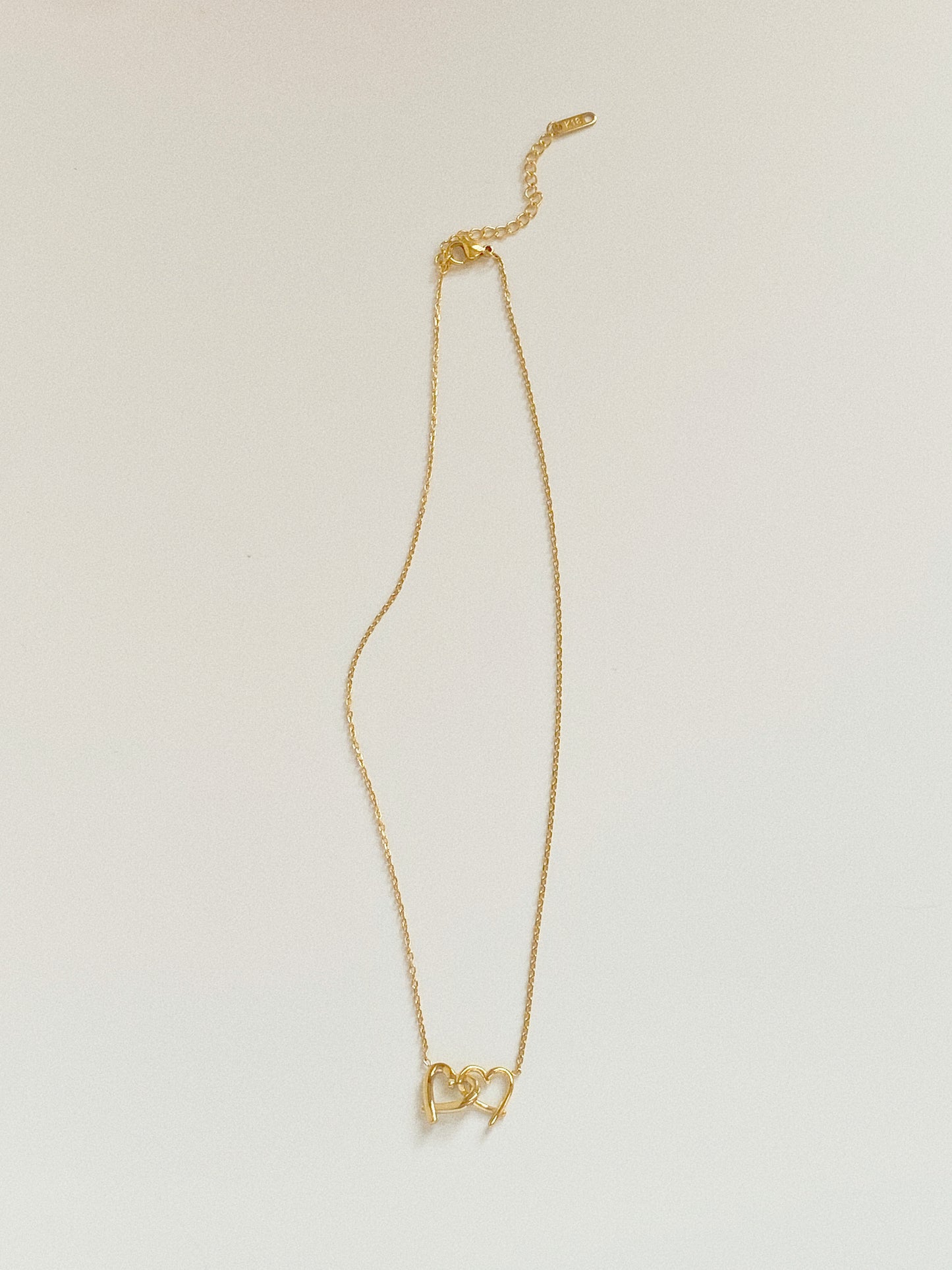 Full view of gold connected hearts necklace showing dainty cable chain and 5cm extender.