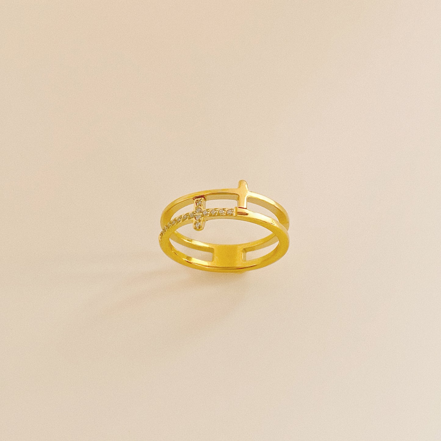 Close up of 18k gold plated stainless steel ring featuring a double band illusion and pave cross.