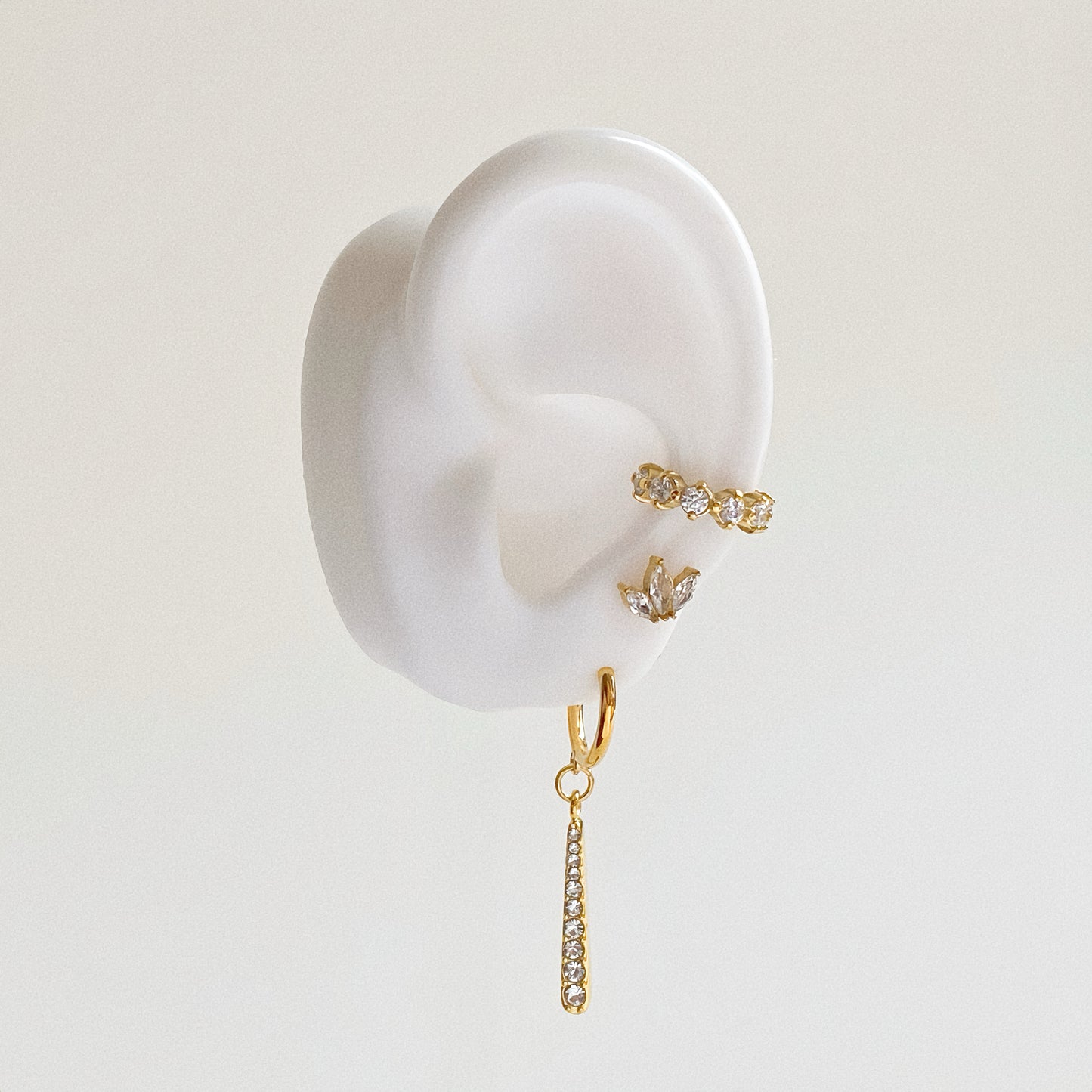 Ear stack styling on model ear featuring Nova Linear Drop Earrings, a crystal ear cuff, and a marquise stud.