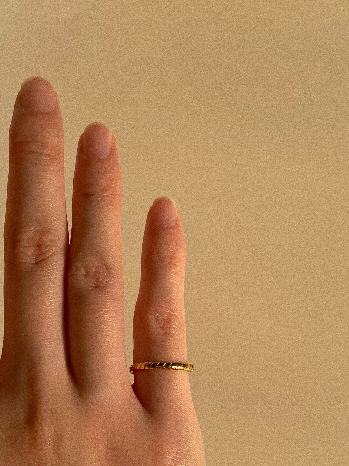 Detailed view of the narrow gold stripe ring on a finger, demonstrating its delicate minimalist fit.