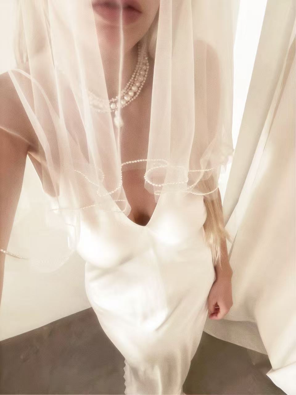 Bride wearing a luxurious 5-layer baroque pearl statement necklace styled with a tulle veil and wedding gown.