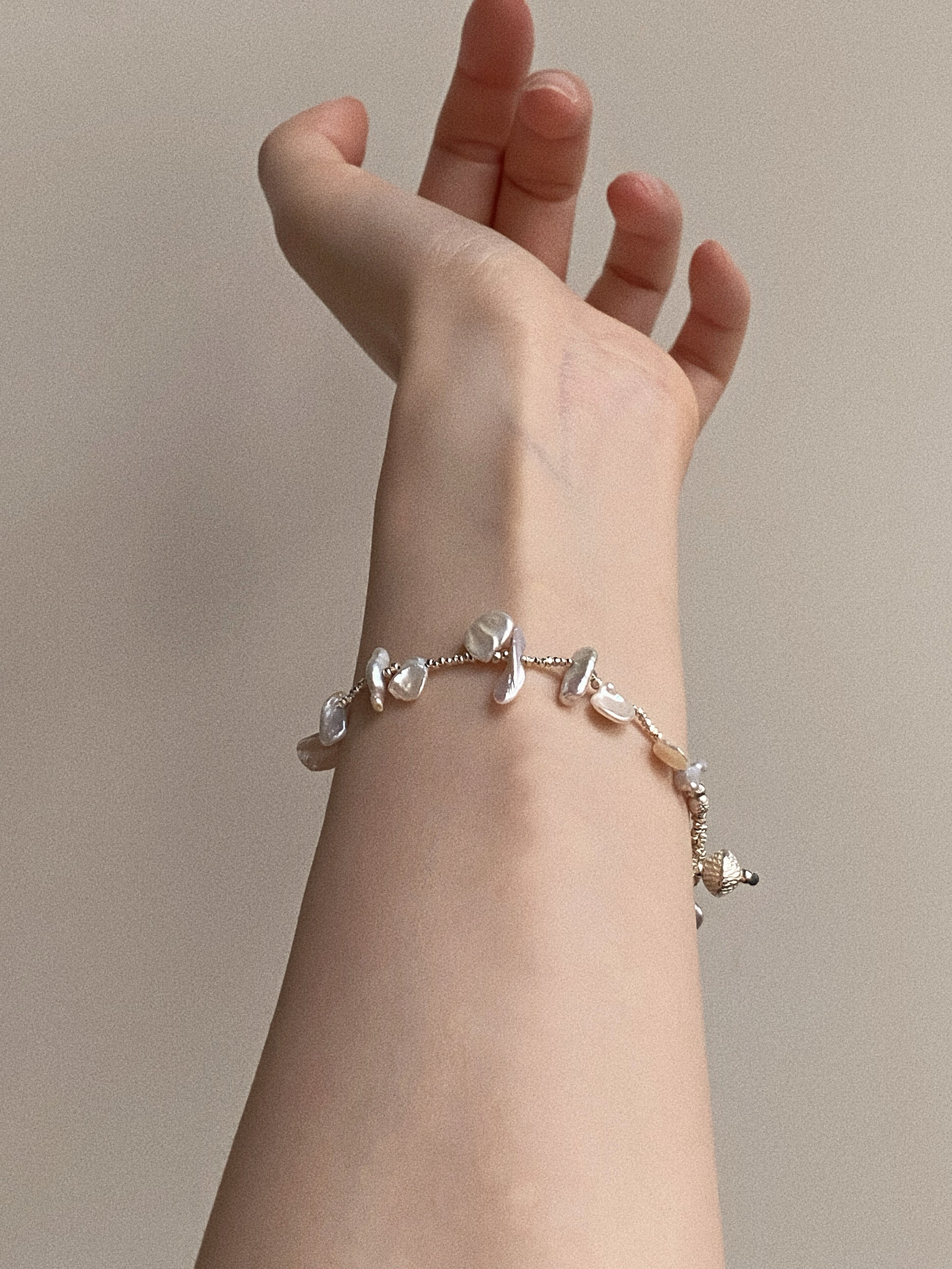 Aesthetic model shot of handmade 925 sterling silver bracelet featuring scattered natural keshi pearls, showing the delicate fit on a woman's wrist.