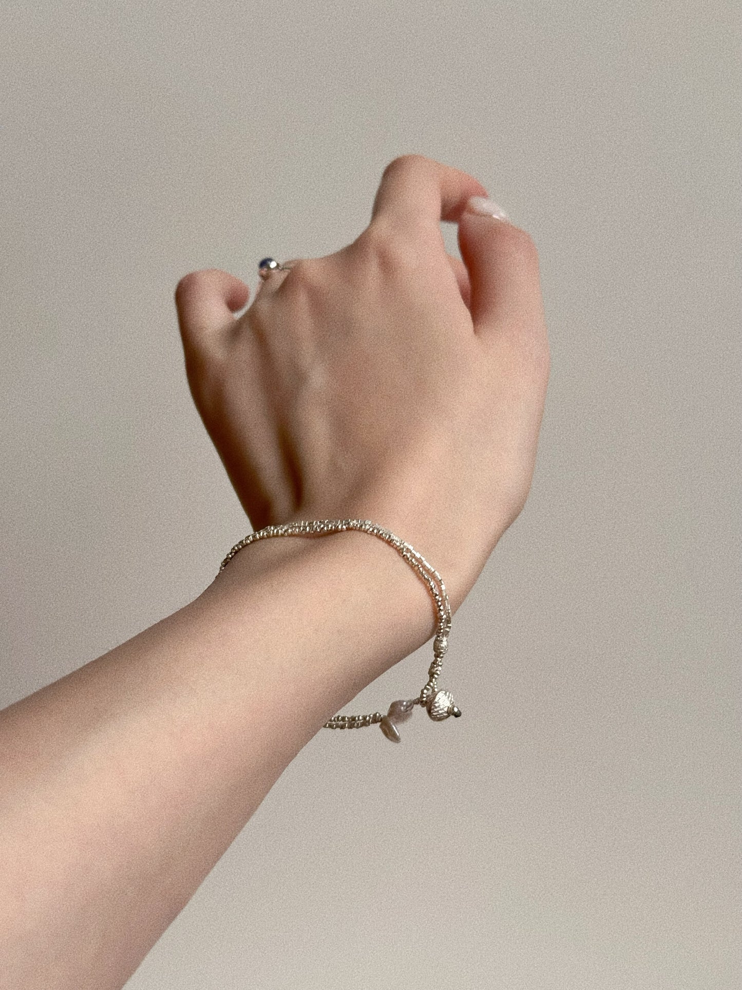 Close up on wrist showing the sparkling handmade faceted silver beads of the double layer bracelet, highlighting the dainty chain texture.