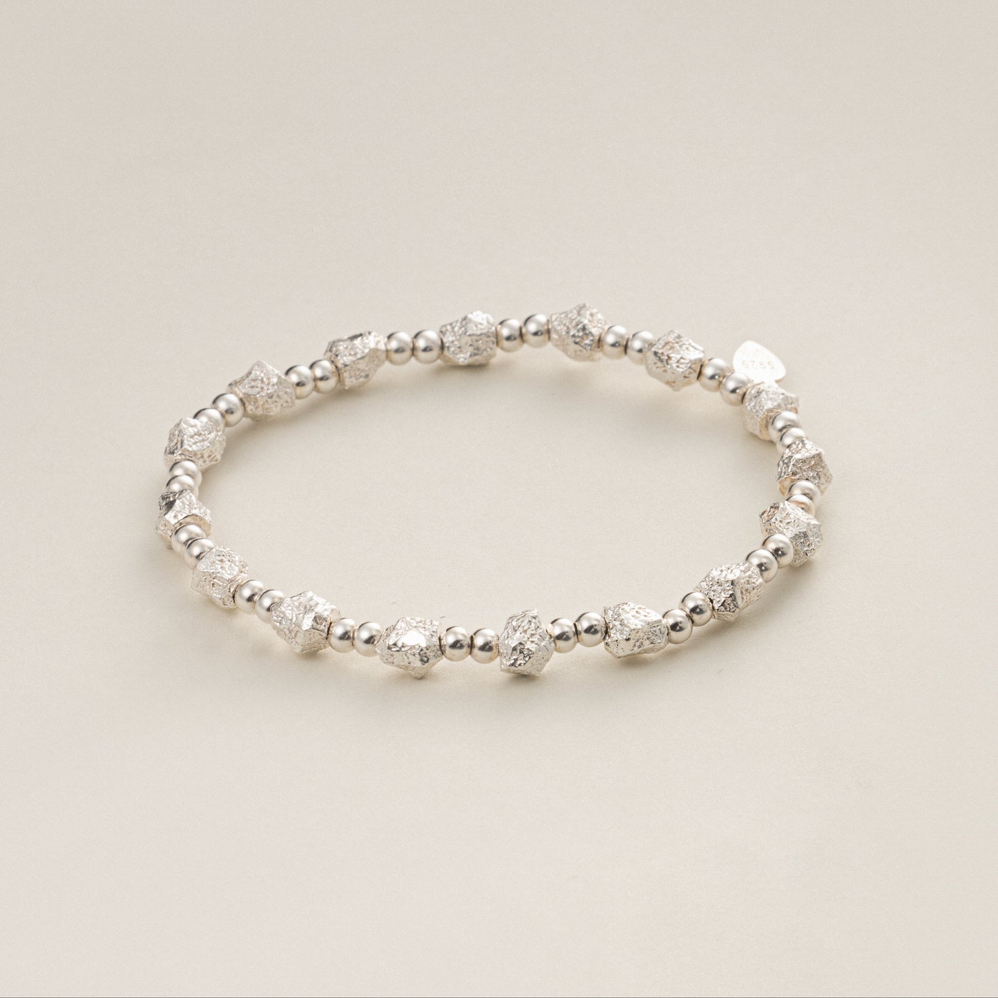 Perspective view of The Luna heavyweight solid 925 sterling silver bracelet, highlighting the unique raw crushed texture of the nugget beads.