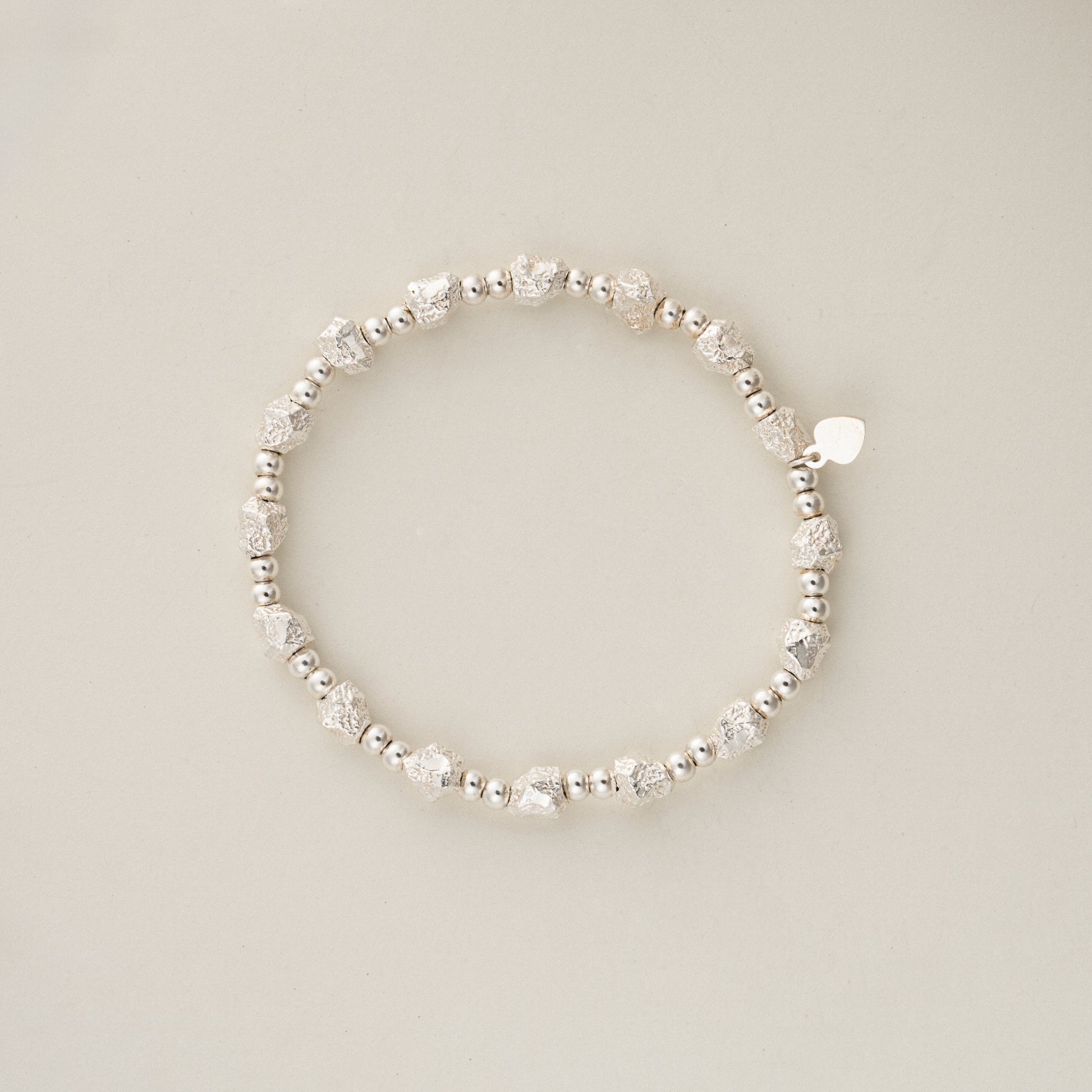 Direct top view flat lay of 11.5g solid sterling silver beaded bracelet, showing the elastic shape and signature S925 heart charm.