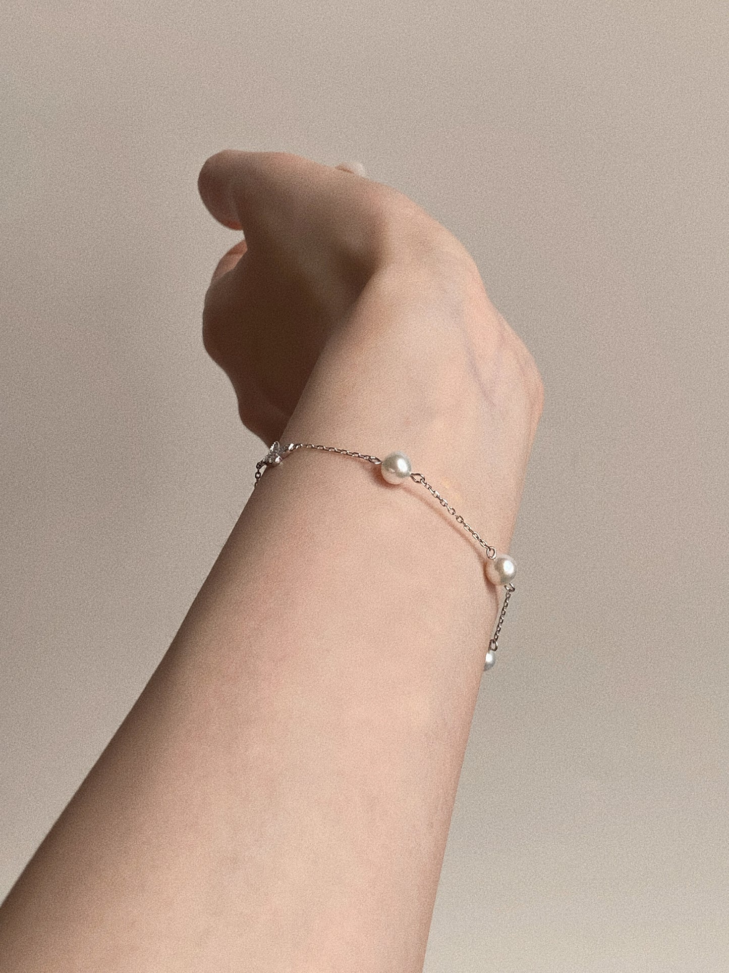 Side profile view of the wrist wearing the floating pearl bracelet, demonstrating the high luster of the near-round natural pearls.