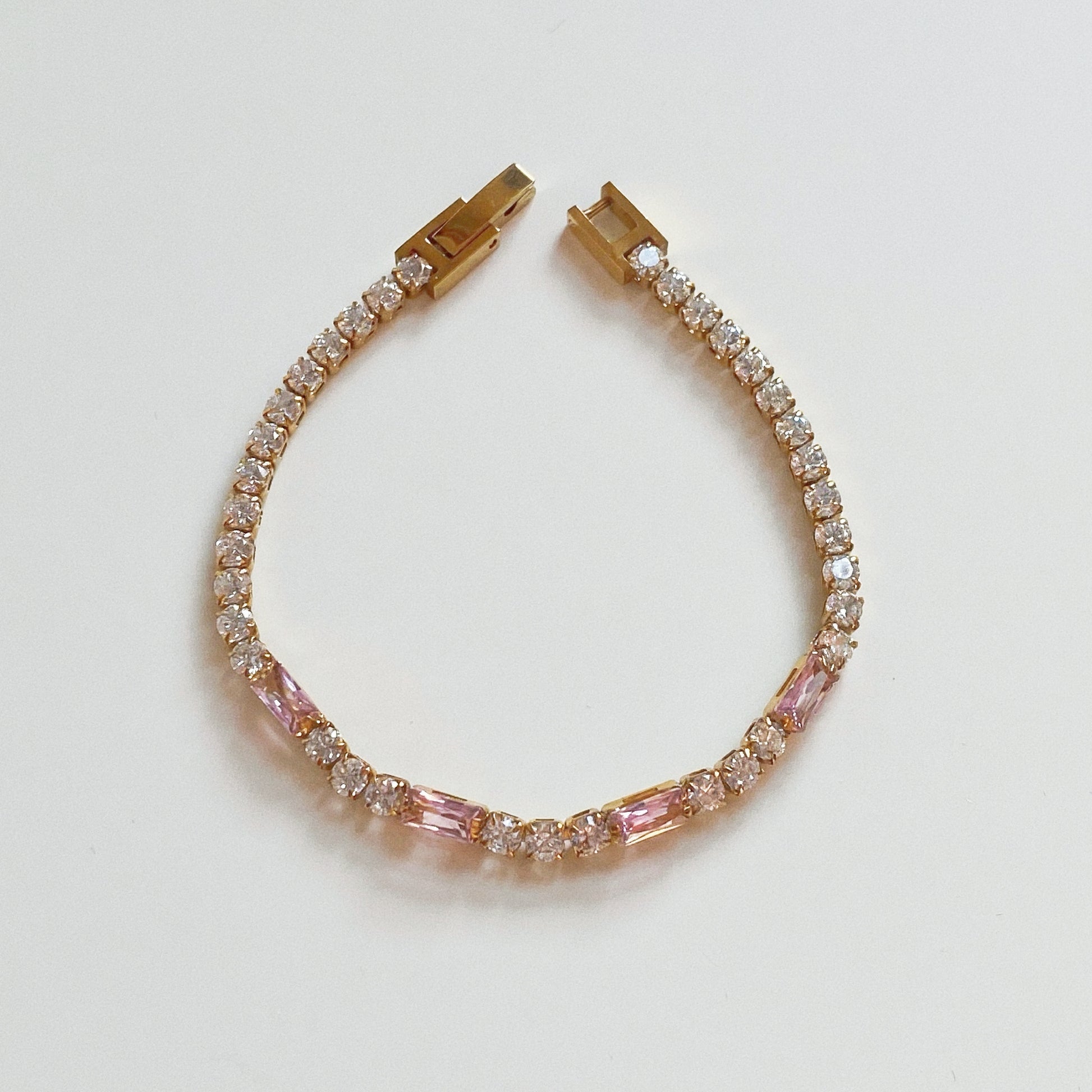 Waterproof gold tennis bracelet featuring alternating pink baguette and clear round cubic zirconia crystals.