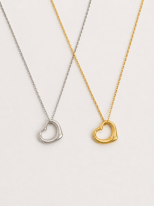Silver and gold floating open heart pendant necklaces shown side by side, dainty 925 sterling silver heart necklaces in both finishes by Deja vu