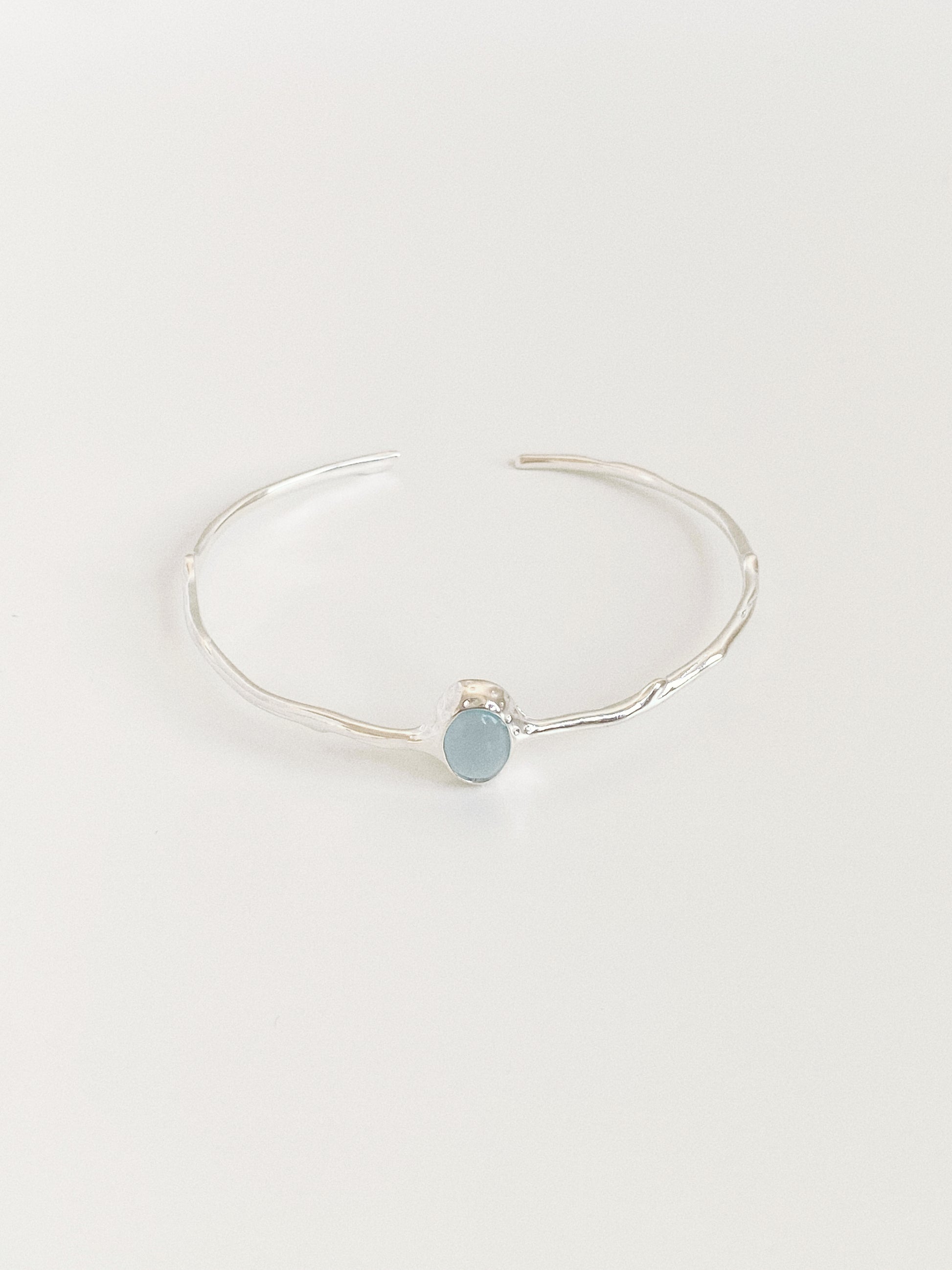 Front view of branch textured sterling silver open bangle set with pale blue aquamarine