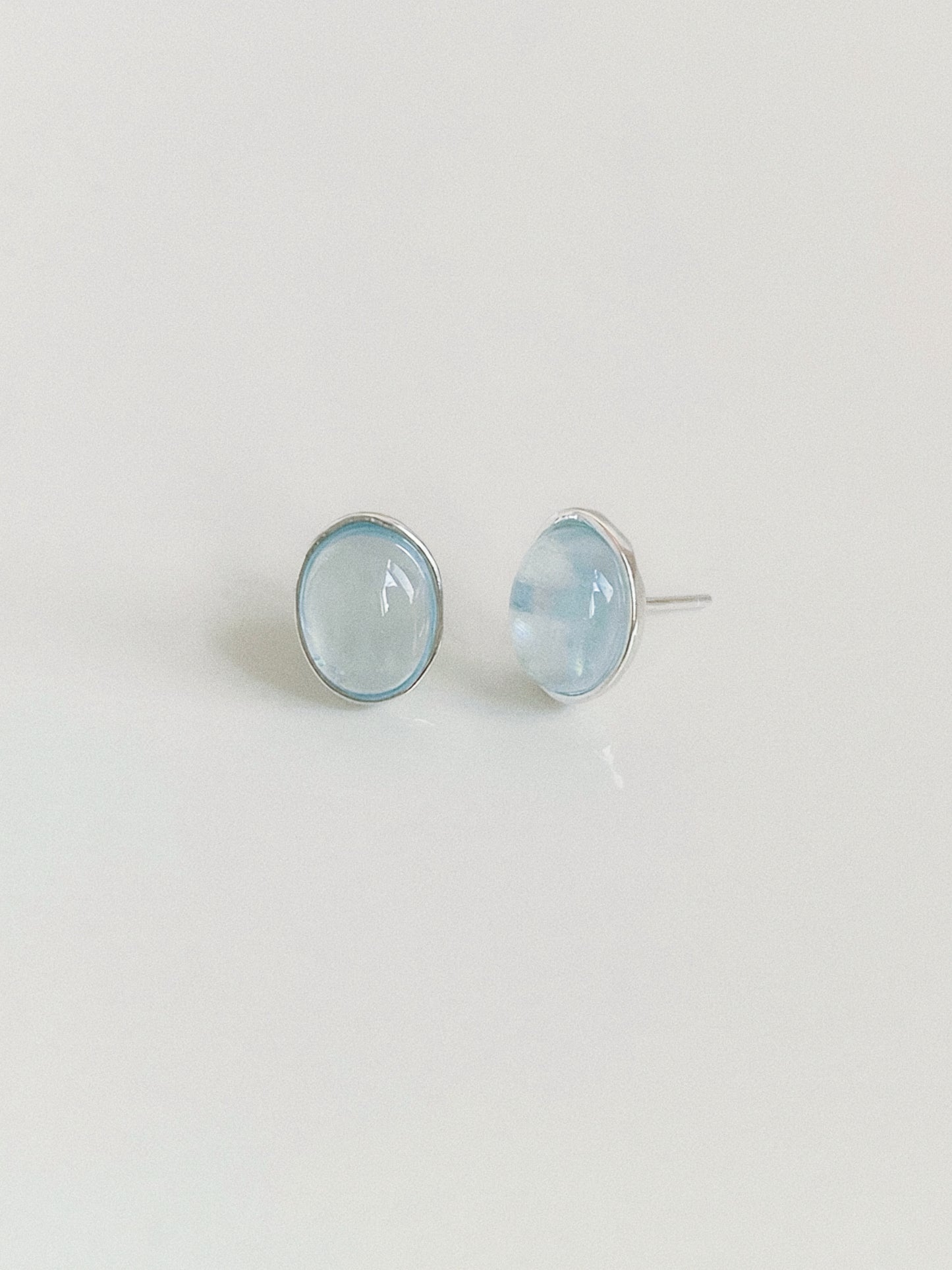 Aquamarine cabochon stud earrings shown from the front and side, revealing the domed stone and silver post