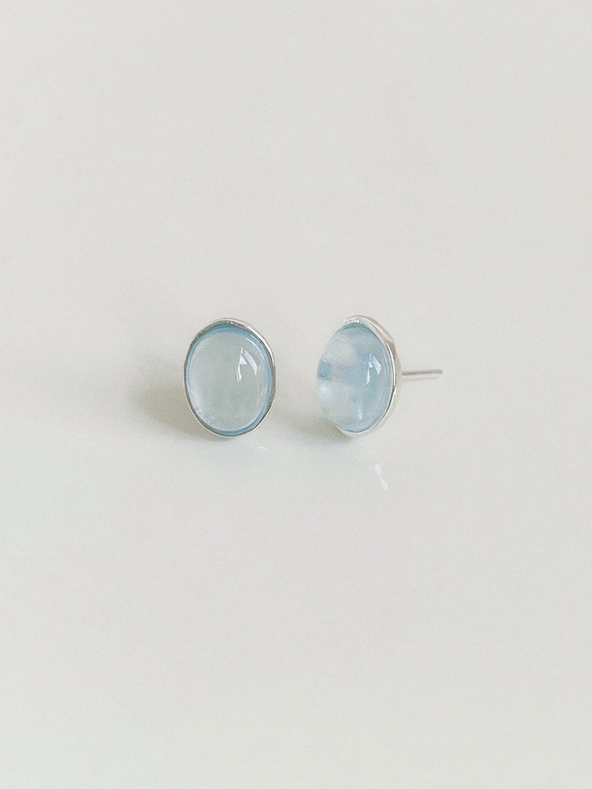 Aquamarine cabochon stud earrings shown from the front and side, revealing the domed stone and silver post