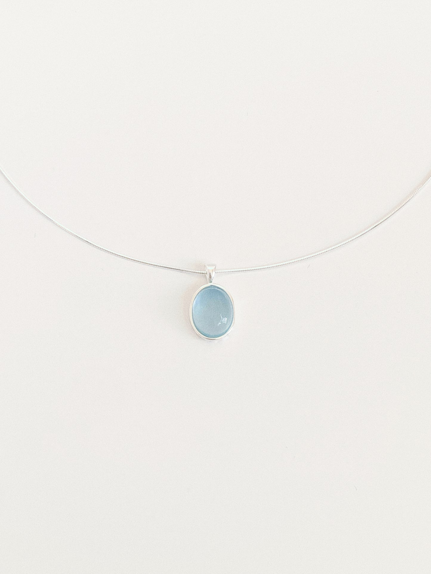 Front view of a soft blue aquamarine cabochon pendant necklace on a smooth 925 silver snake chain