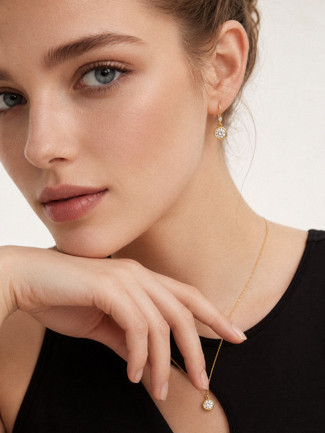 Model wearing the earrings and necklace from the Aura waterproof jewellery set in 18k gold