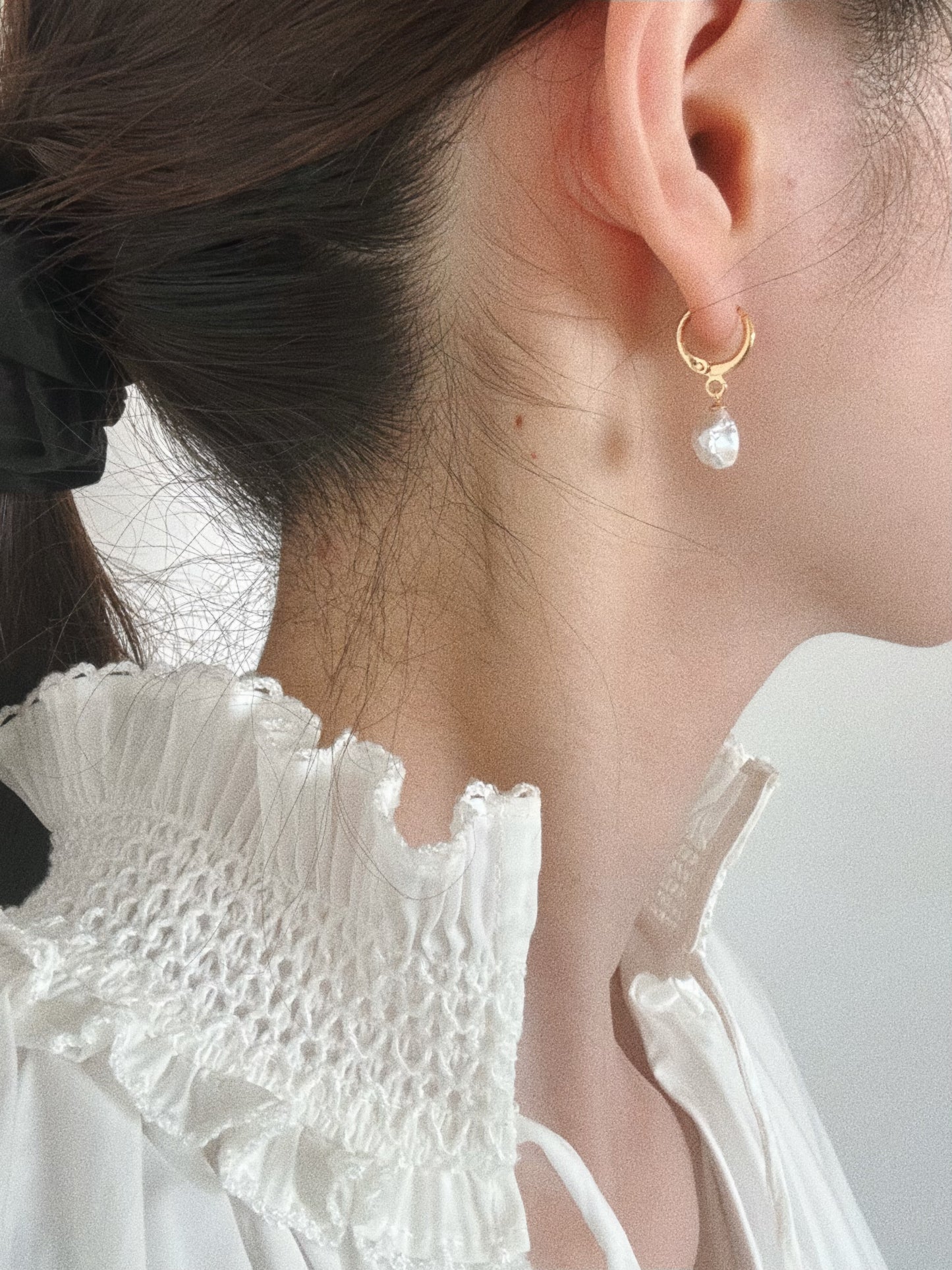Baroque pearl huggie hoop earring worn on model showing side profile and earlobe styling