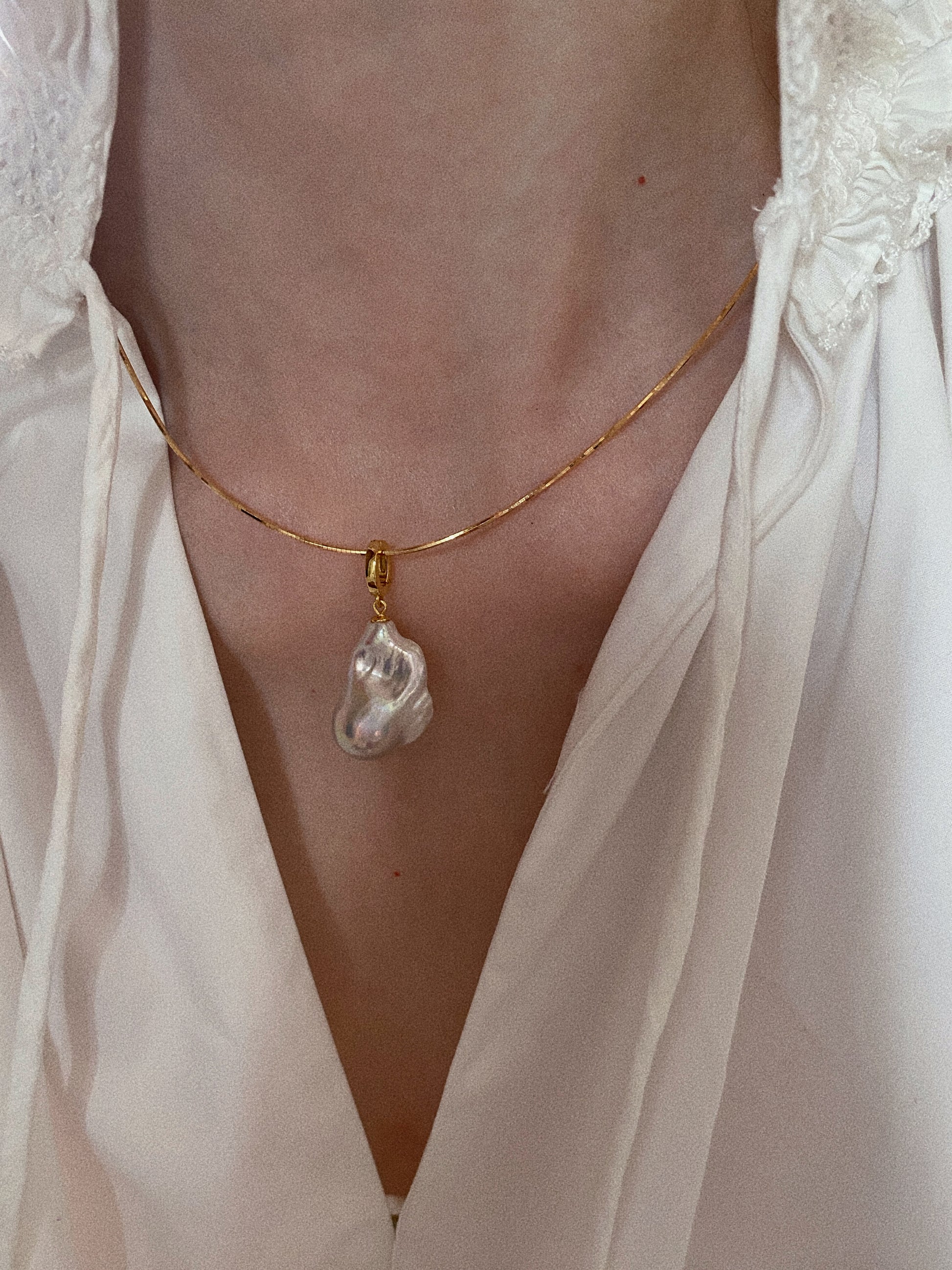 Snake chain choker with baroque fishtail freshwater pearl pendant styled on model in white blouse