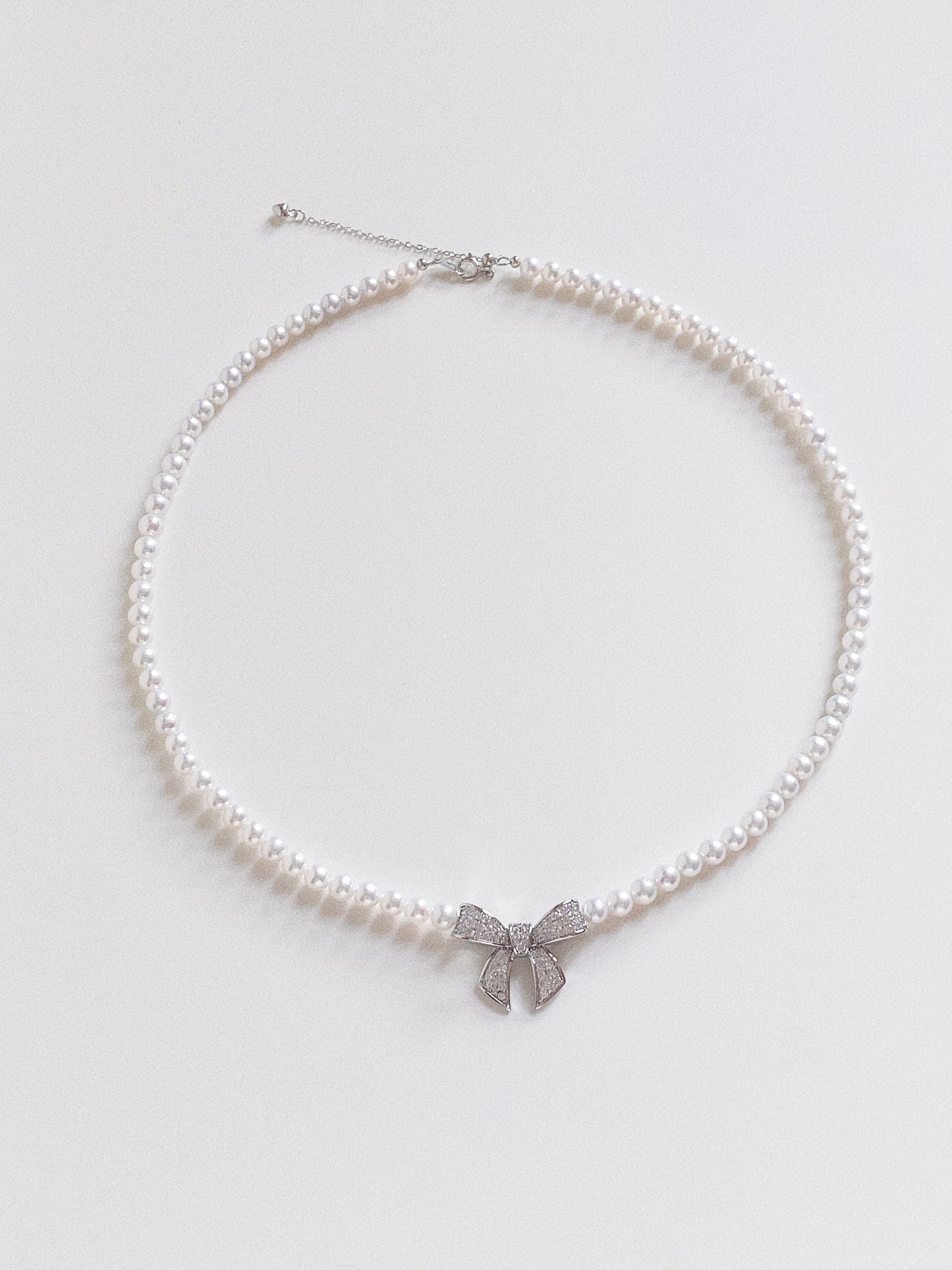 Flat lay of the natural pearl bow necklace showing the 44cm length and S925 sterling silver extender chain.