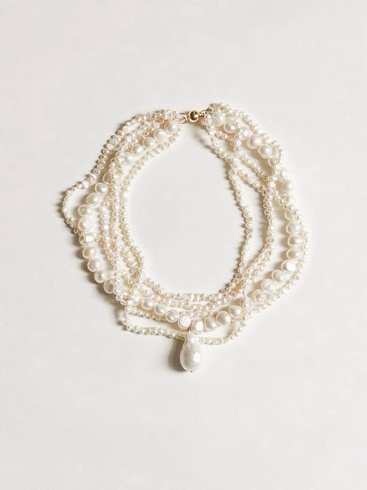 Flat lay of the full Aphrodite Necklace, displaying all 5 strands and the 18k gold plated clasp mechanism.