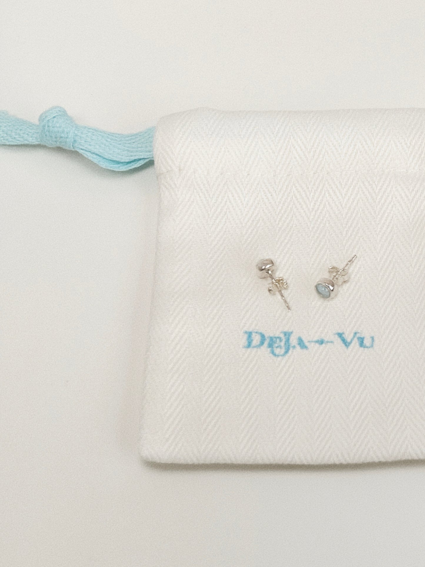 Natural blue topaz stud earrings styled with Deja Vu Jewellery branded embroidered pouch