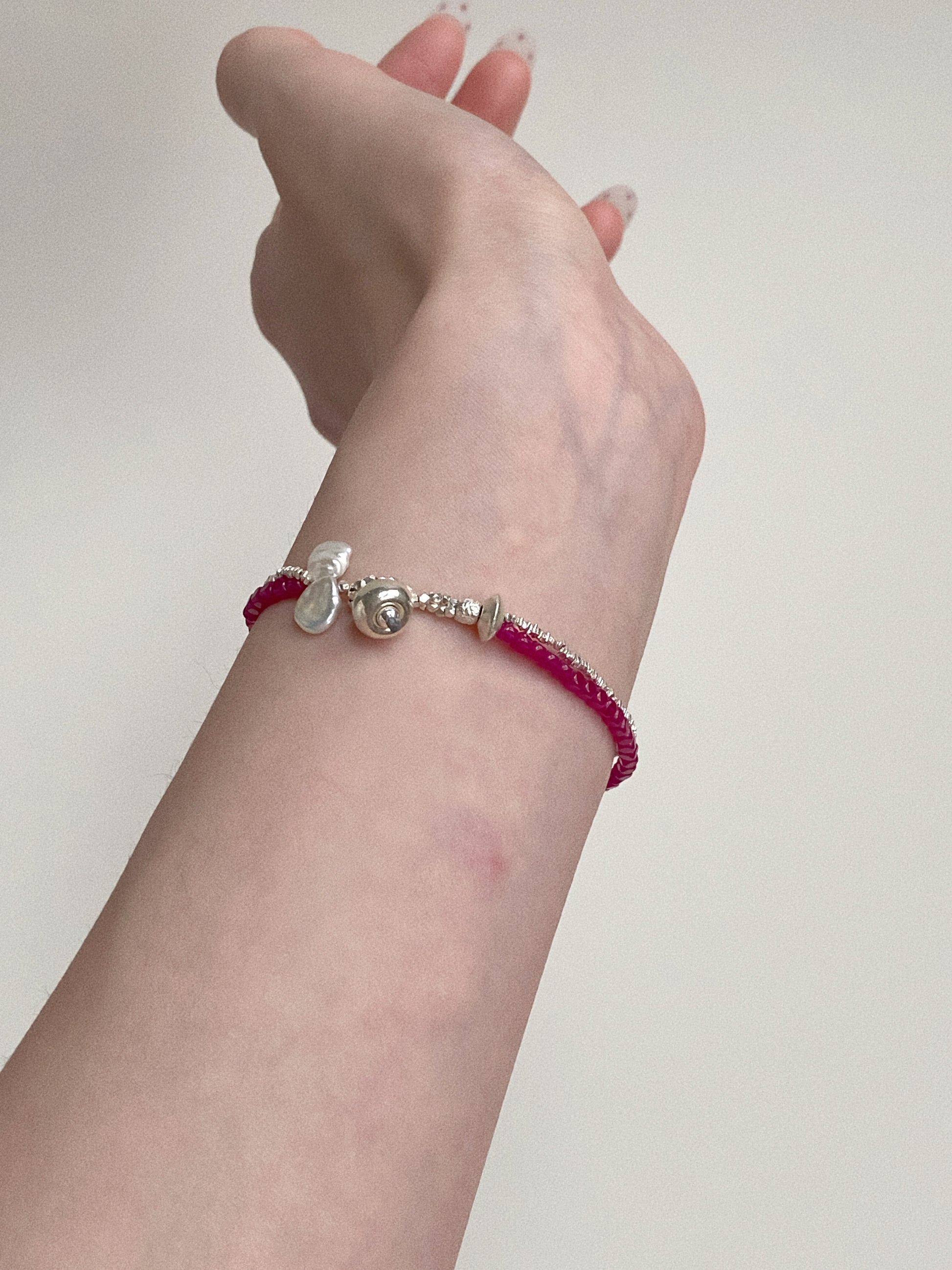 Side view of the Deja vu Jewellery red corundum and pearl bracelet showing the elegant drape on a 14cm wrist.