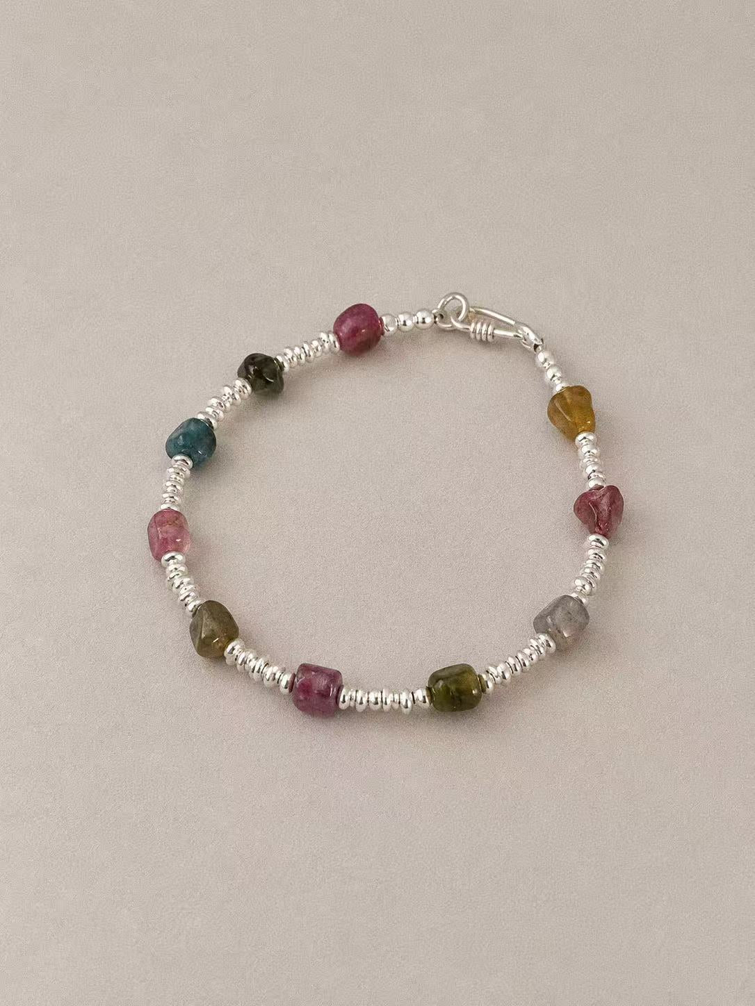 Angled view of the Bonbon bracelet with pink, green, blue-green and honey-toned tourmaline between silver disc spacers.