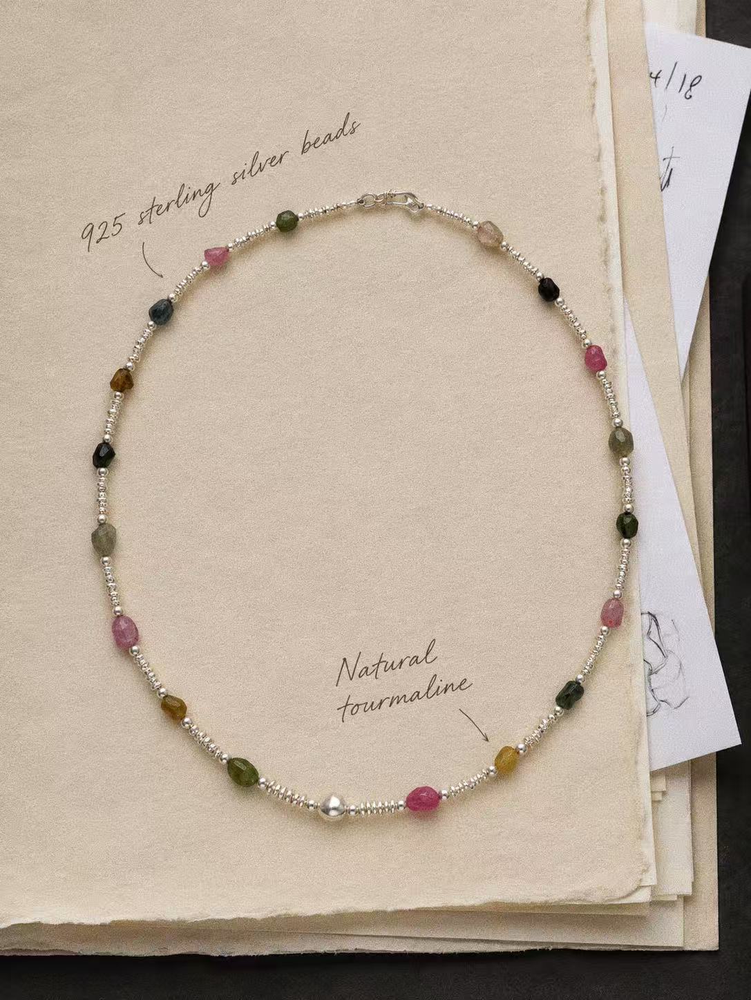 Bonbon natural tourmaline and 925 sterling silver necklace arranged on a cream book page