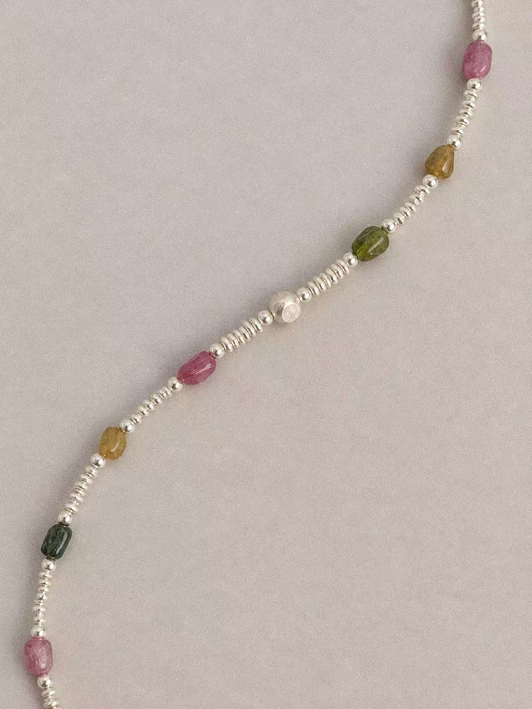 Diagonal detail of natural tourmaline pebbles alternating with irregular sterling silver disc spacers