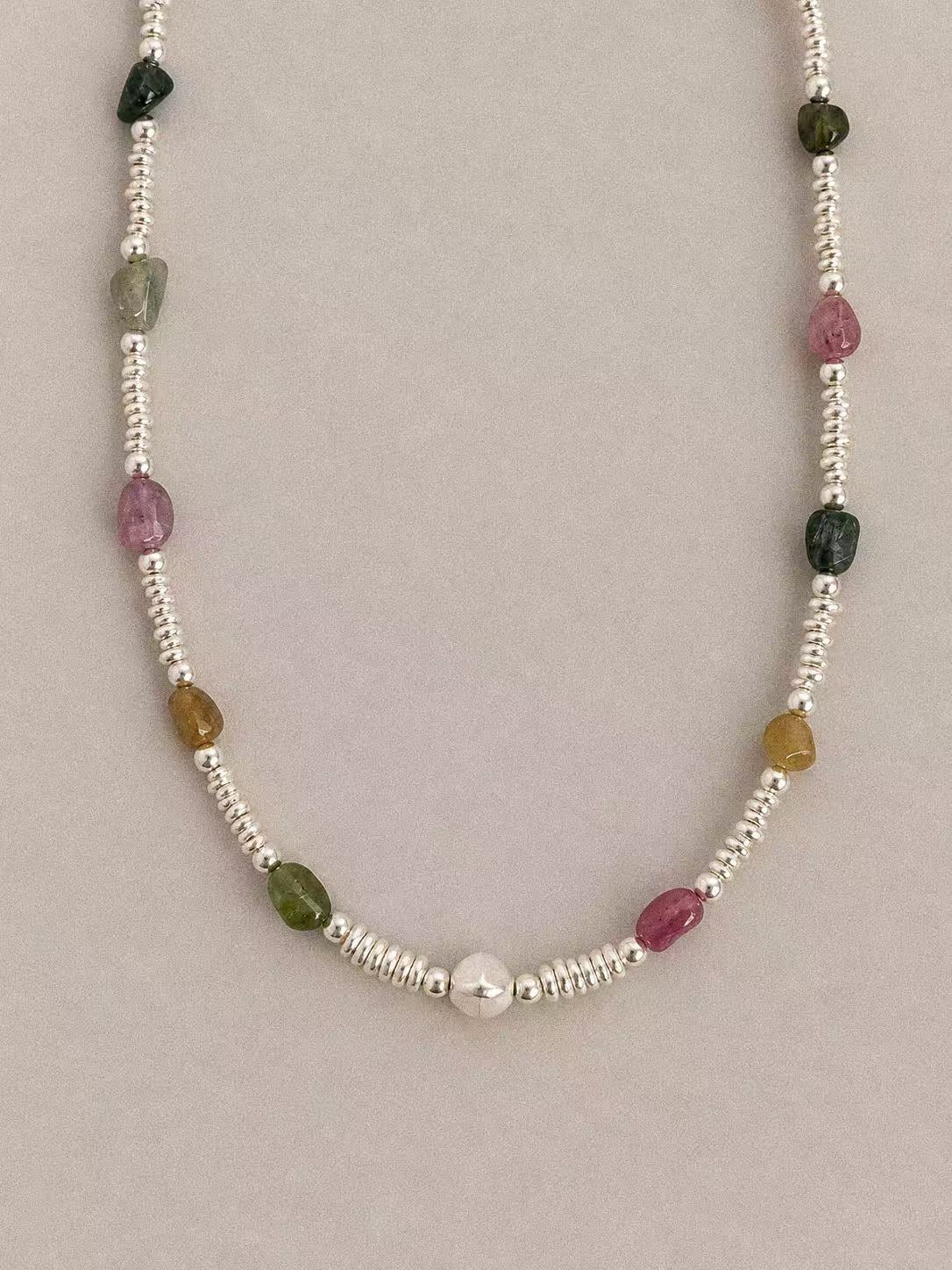 Close-up of multicolour tourmaline beads, irregular silver discs and the central sterling silver bead