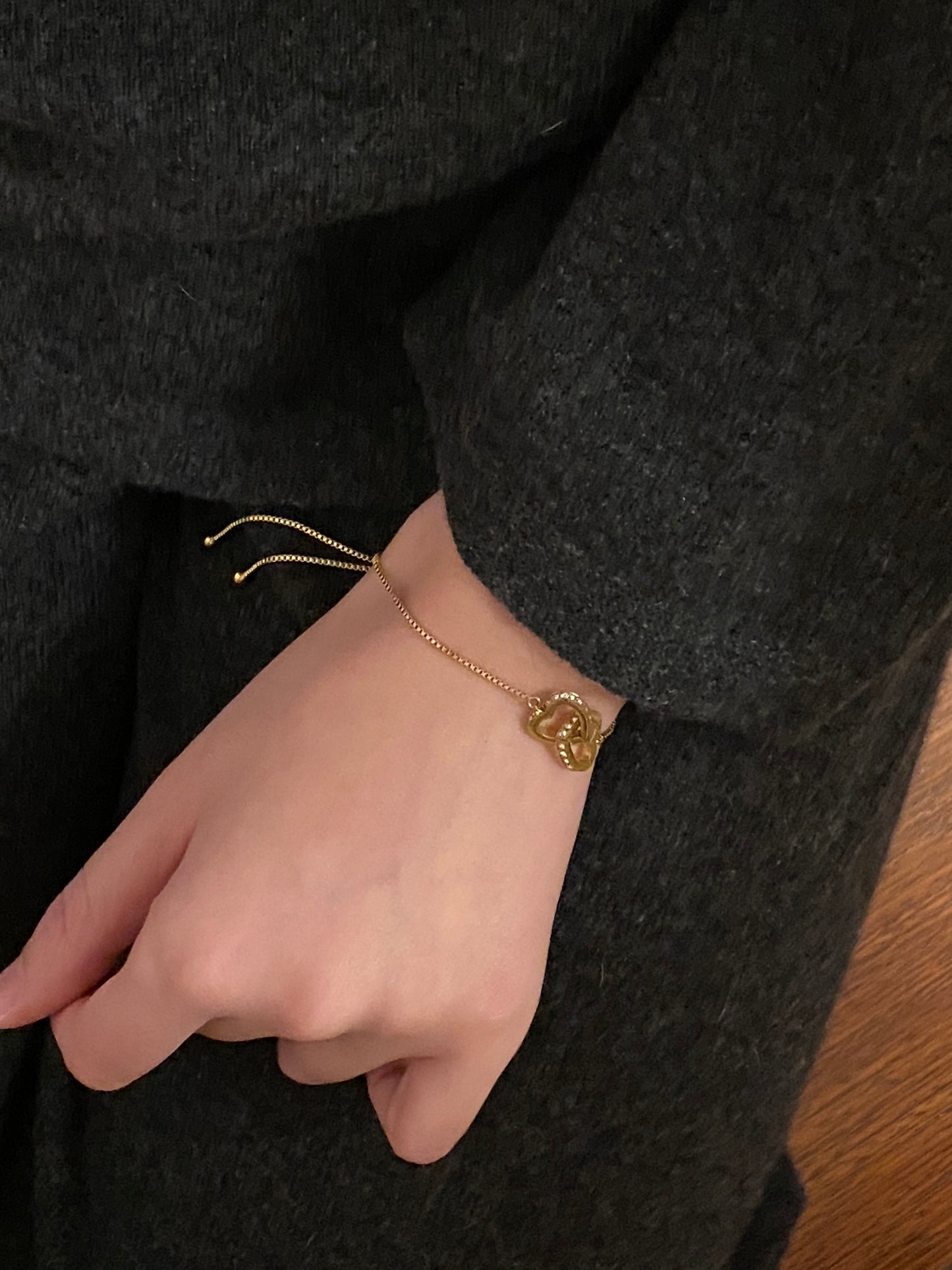 Woman wearing adjustable heart bracelet showing the decorative bead ends of the slider chain.