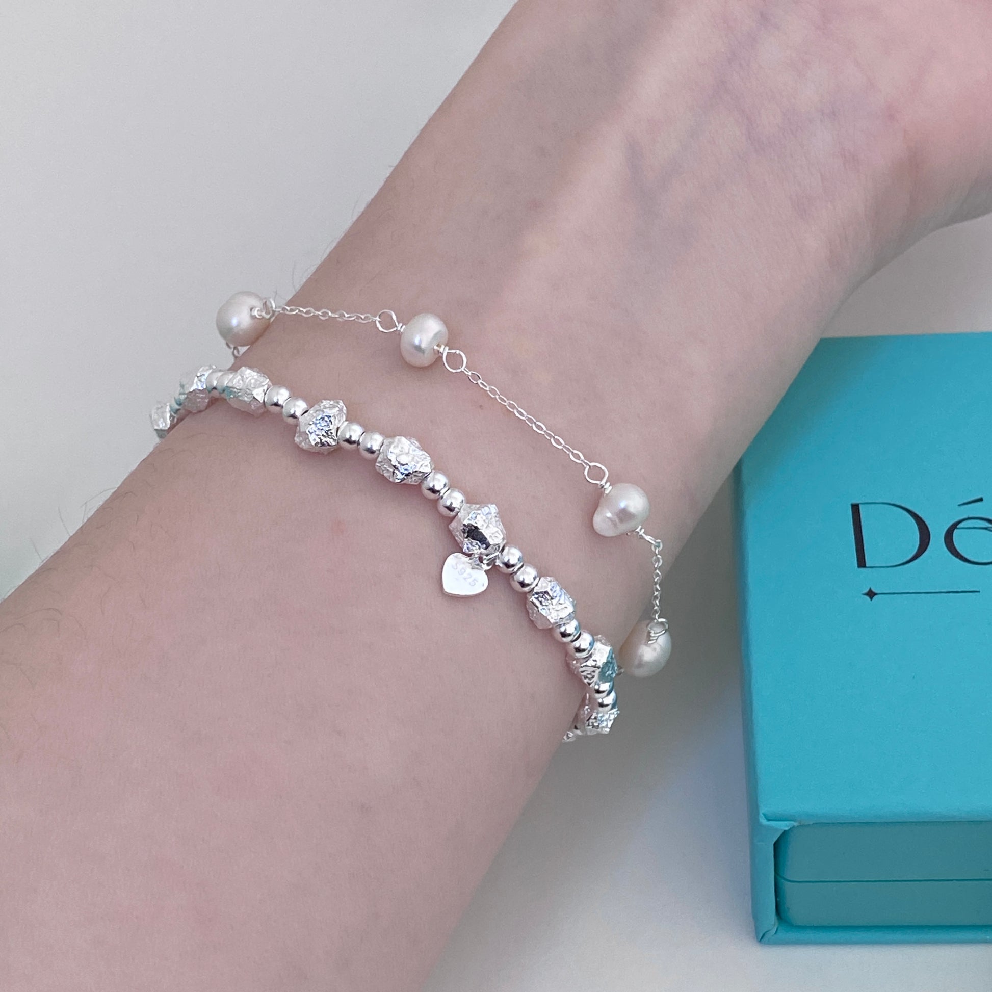 Model wearing The Luna Heavyweight Silver Bracelet stacked with a pearl bracelet, showing the size and fit on the wrist.