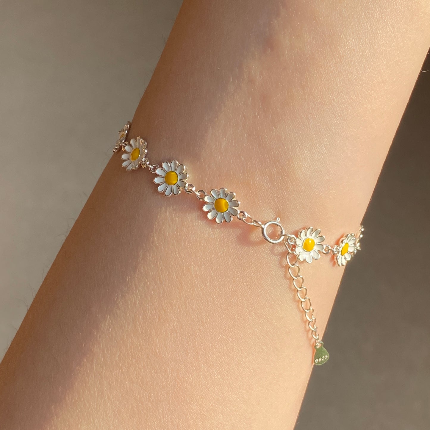 Detail of clasp and daisy charms on delicate floral bracelet