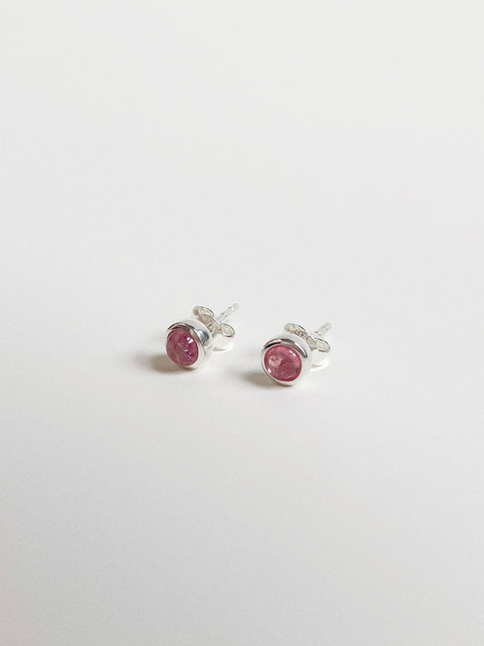 Angled view of rose pink tourmaline studs showing the smooth dome cabochon cut and silver bubble setting.