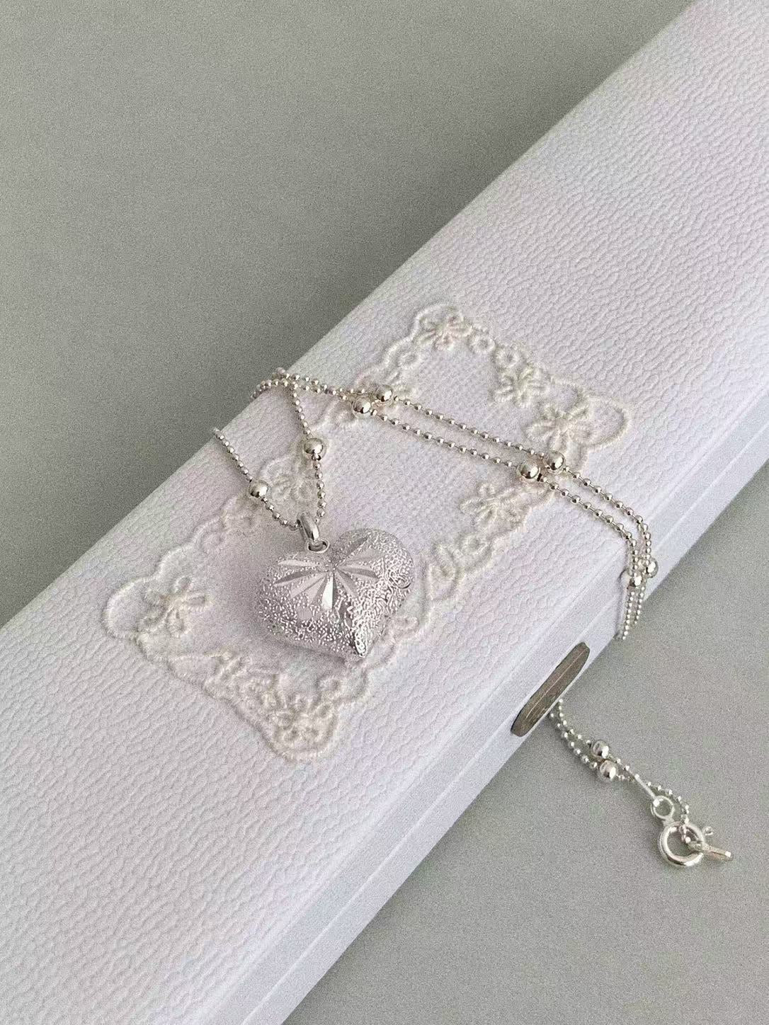 Bubble Heart necklace on a white embroidered jewellery box, showing the silver bead chain and spring ring clasp.