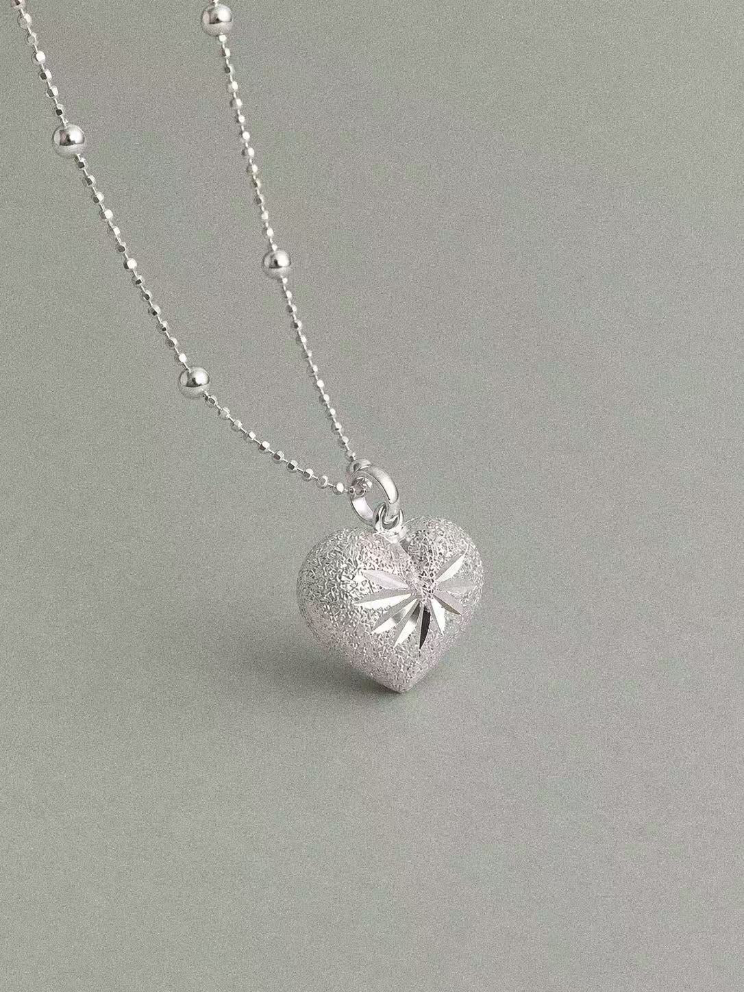 Bubble Heart sterling silver pendant with engraved starburst detailing on a silver bead chain.