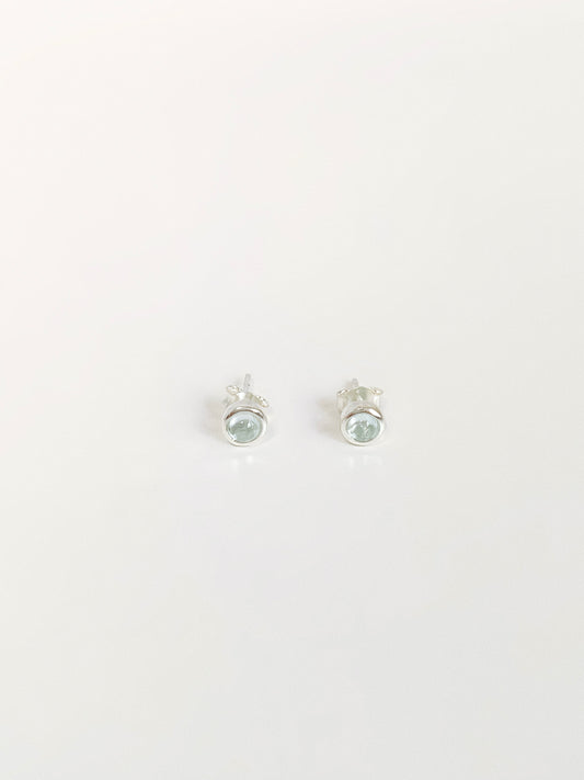 Natural blue topaz cabochon stud earrings in 925 sterling silver bezel flat lay by Deja Vu Jewellery