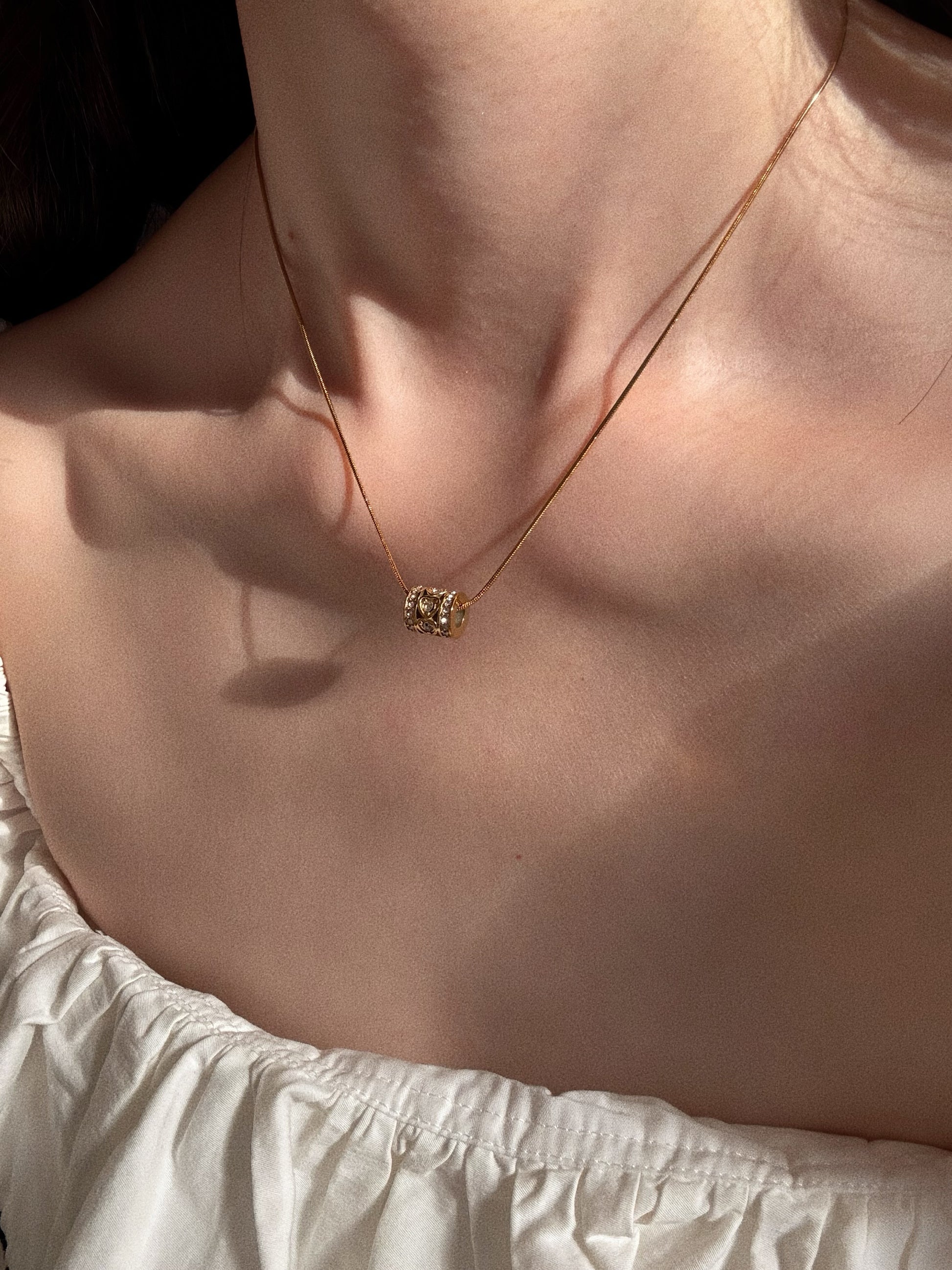 Model wearing the Kaleidoscope Love Necklace, showing how the liquid gold snake chain sits on the collarbone.