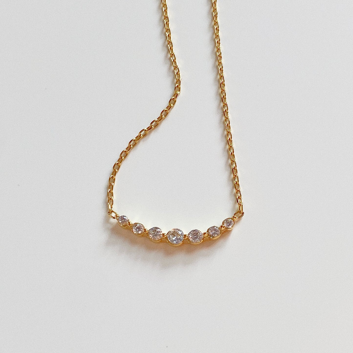Detail shot of the curved crystal bar setting on an 18k gold plated stainless steel chain.