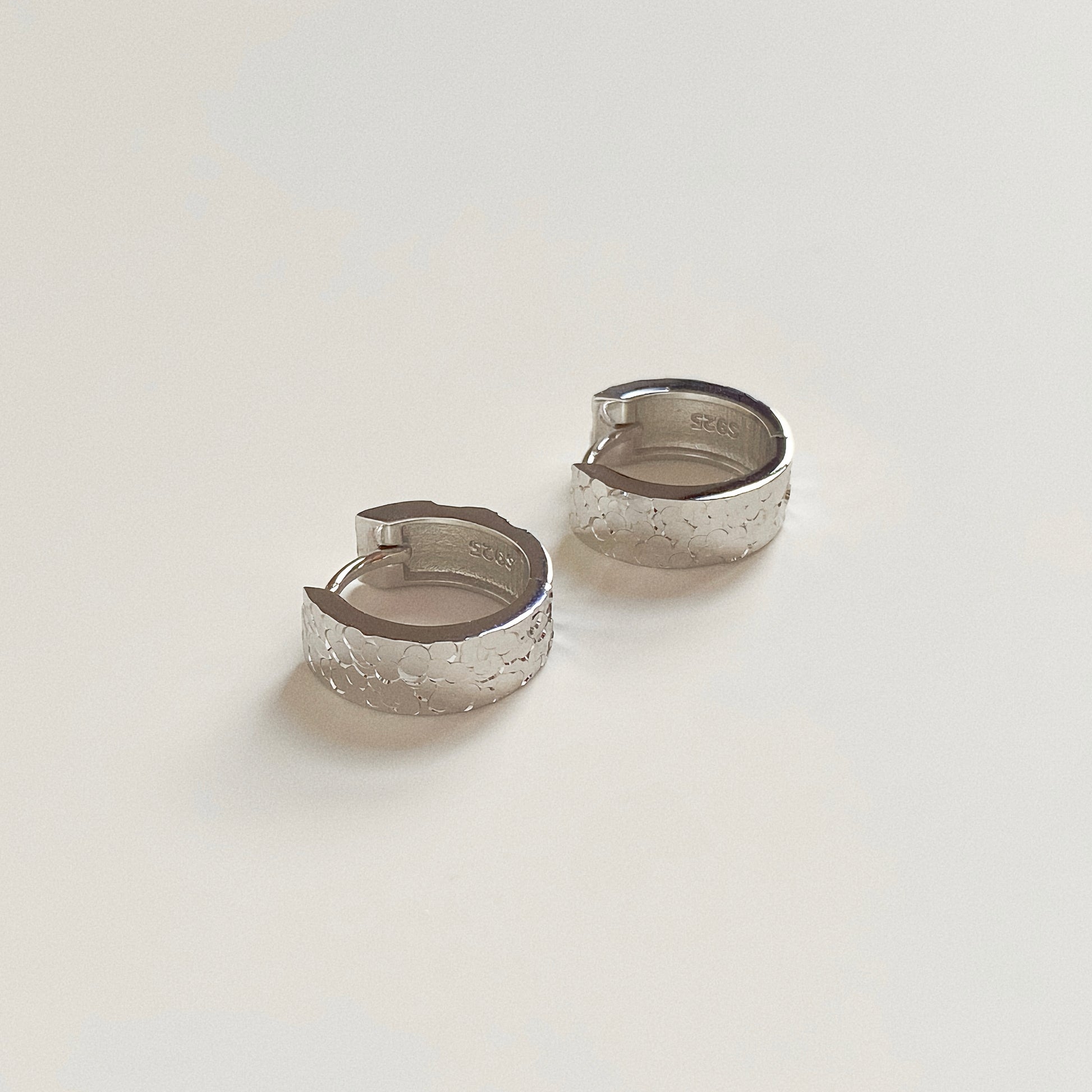 Solid Sterling Silver hoop earrings lying flat, showing S925 hallmark stamp and thick durable design.