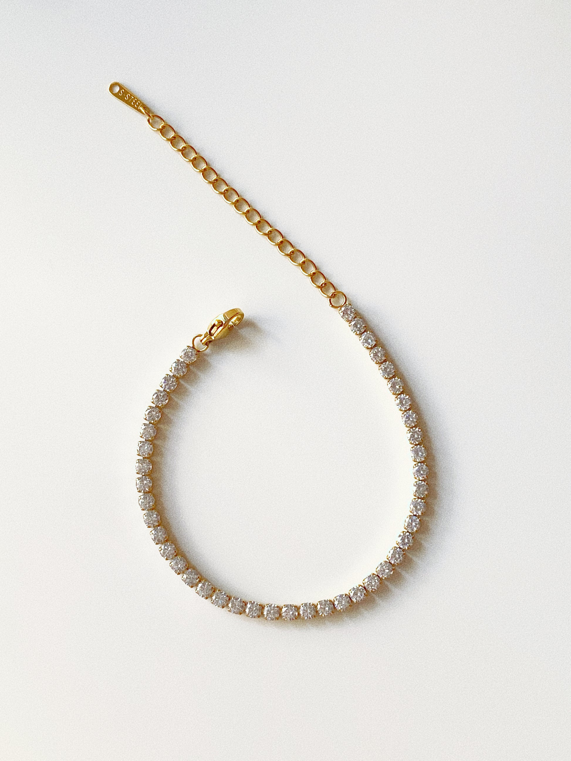 Classic waterproof gold tennis bracelet in stainless steel with cz stones and extension chain flat lay by Deja Vu Jewellery