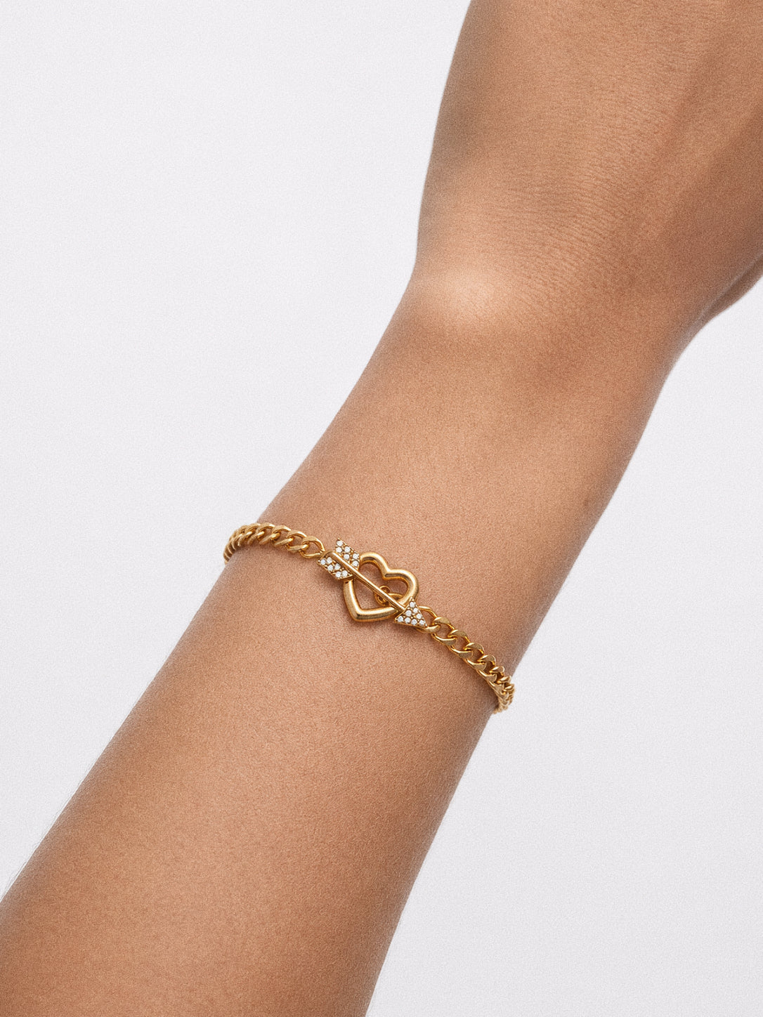 Model wearing the Cupid curb chain bracelet with the heart and arrow toggle sitting on top of the wrist