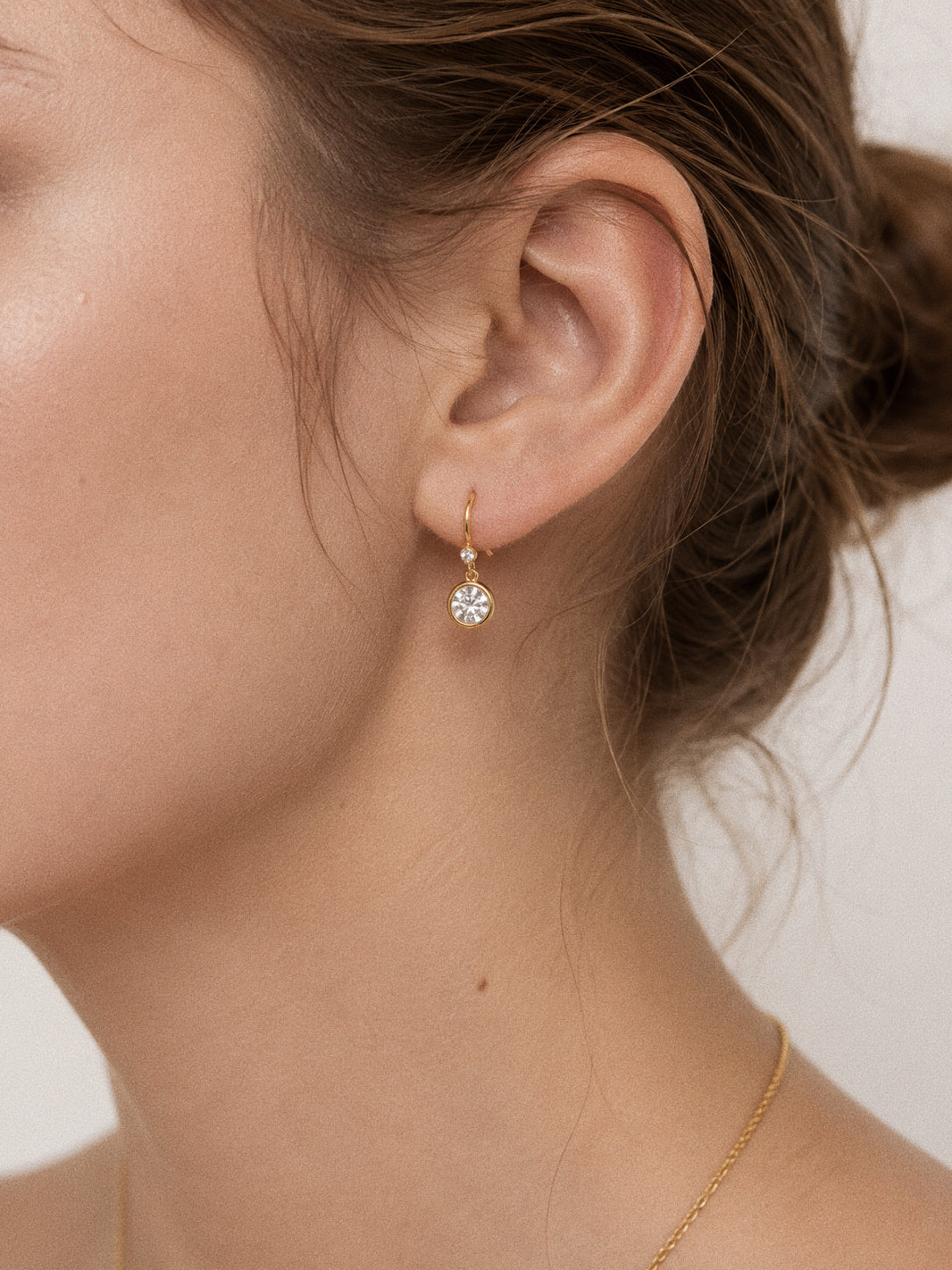 Model wearing the Aura cubic zirconia drop earring in 18k gold showing the 2.7cm drop length