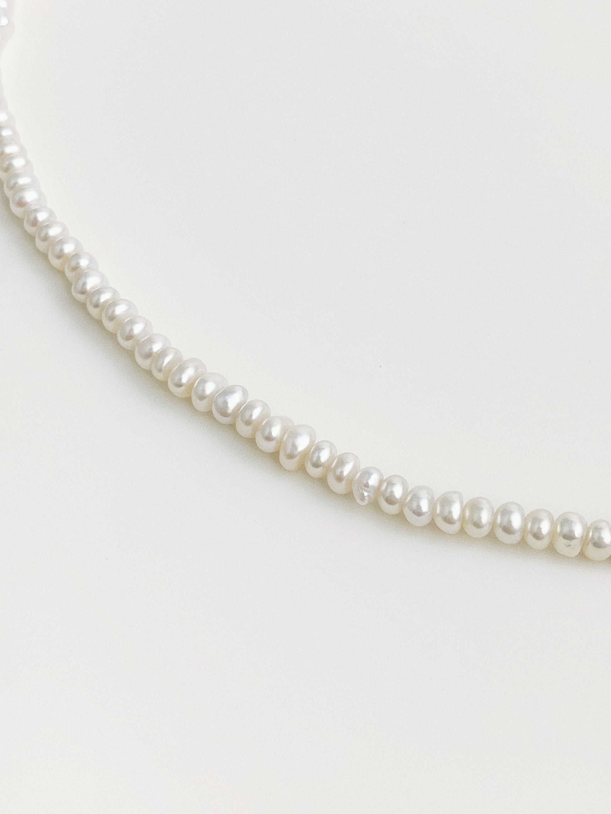 Close-up of dainty button-shape freshwater pearls strung as fine choker necklace