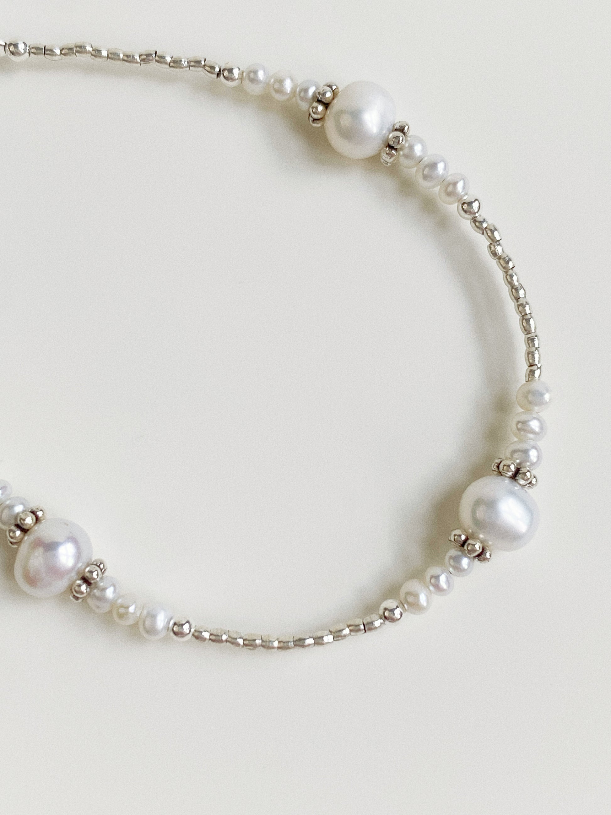 Close-up shot showing the detailed faceted silver beads and natural pearls on a professional steel wire.