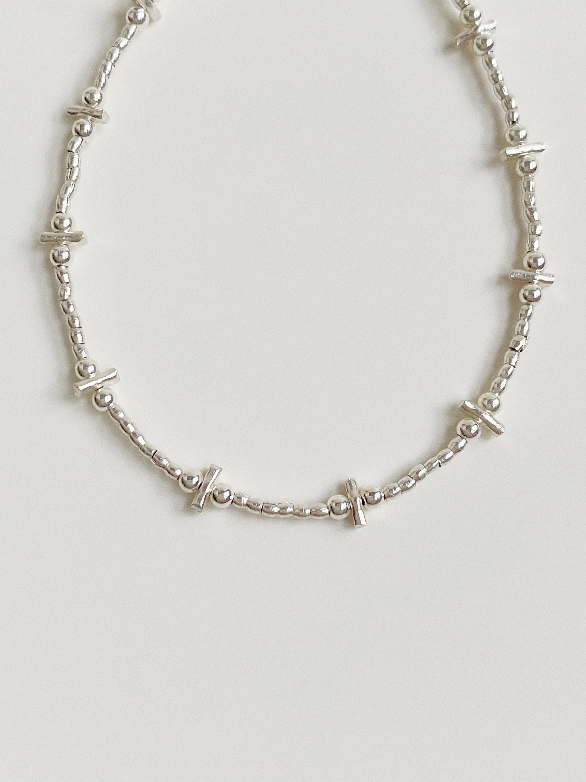 Close up view of the alternating silver bars and beads strung on steel wire, highlighting the polished finish.