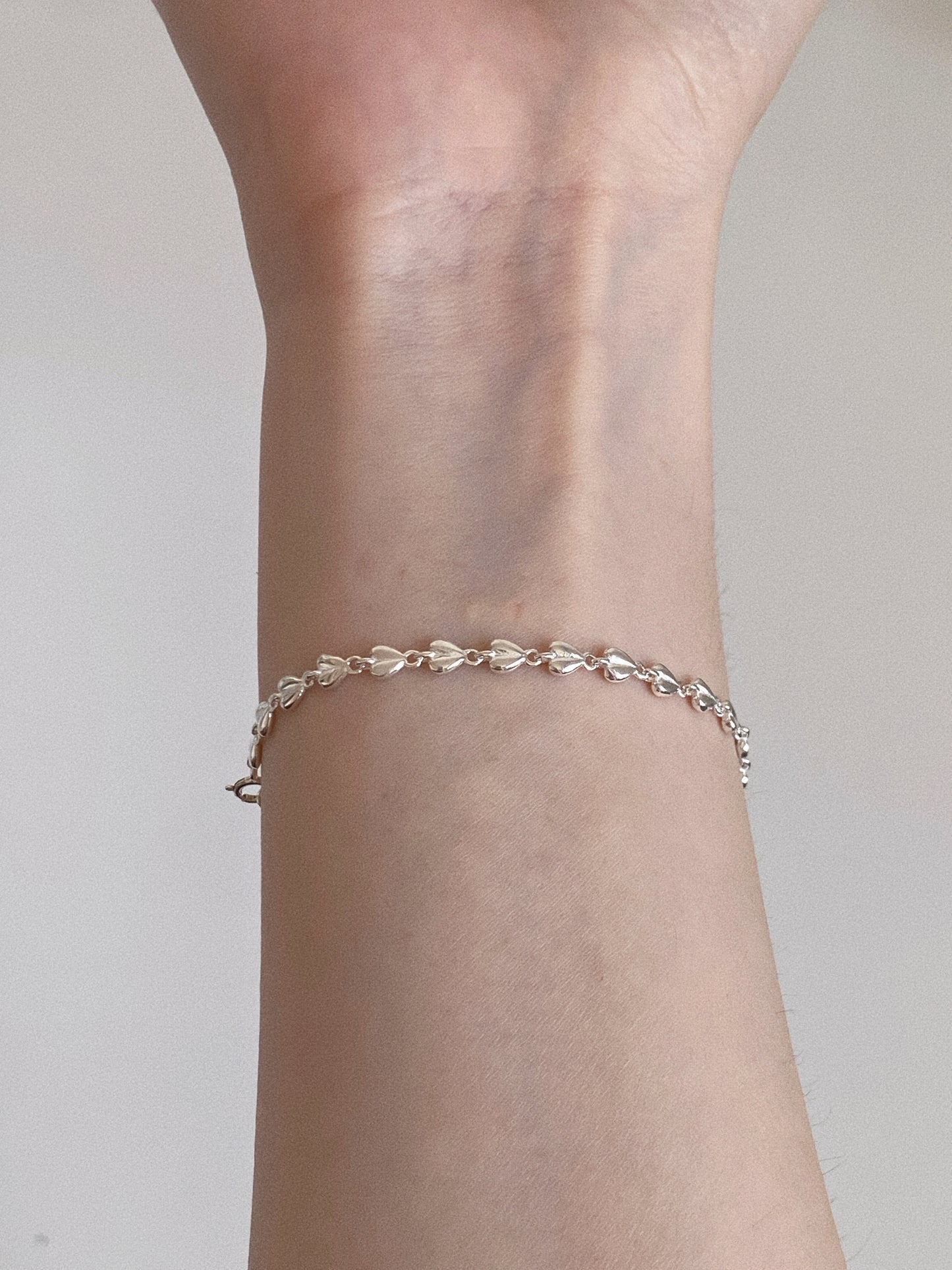 Sterling silver puffed heart chain bracelet worn alone on a slim wrist, showing its delicate everyday scale