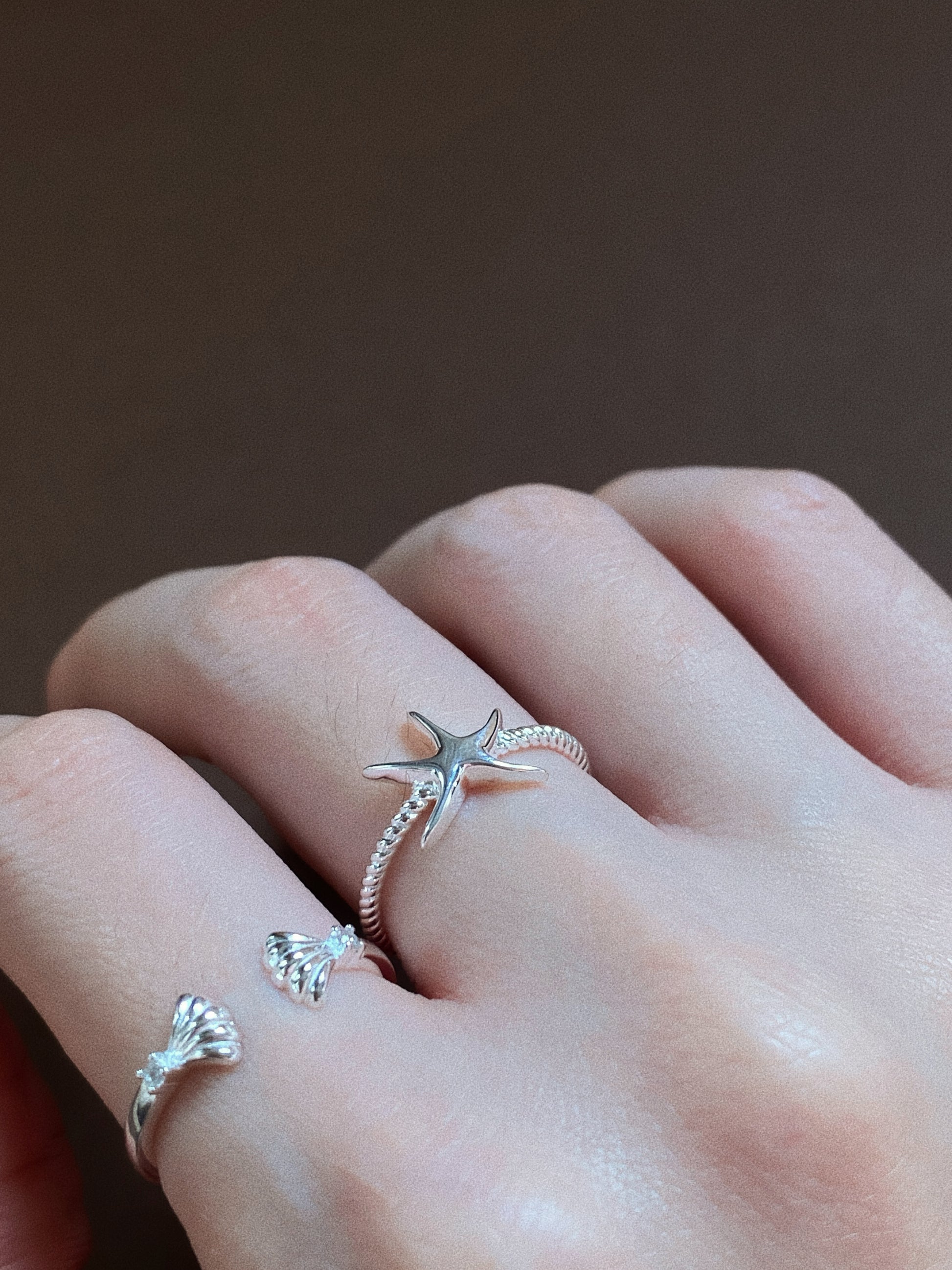 Detail shot of the Oceania Drift starfish ring on a finger, highlighting the intricate 925 silver craftsmanship and the adjustable open-band design.