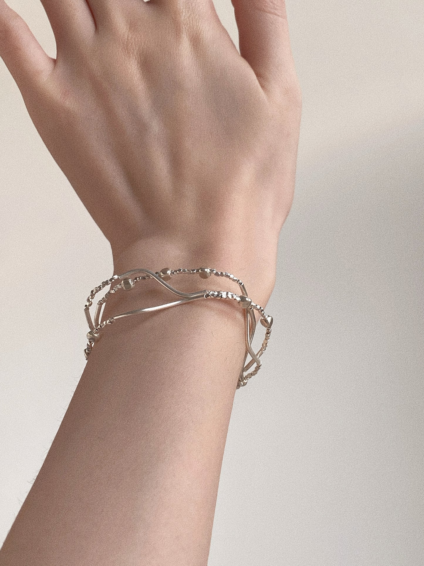Dainty handmade triple-layer 925 sterling silver wave bracelet on woman's wrist for everyday styling