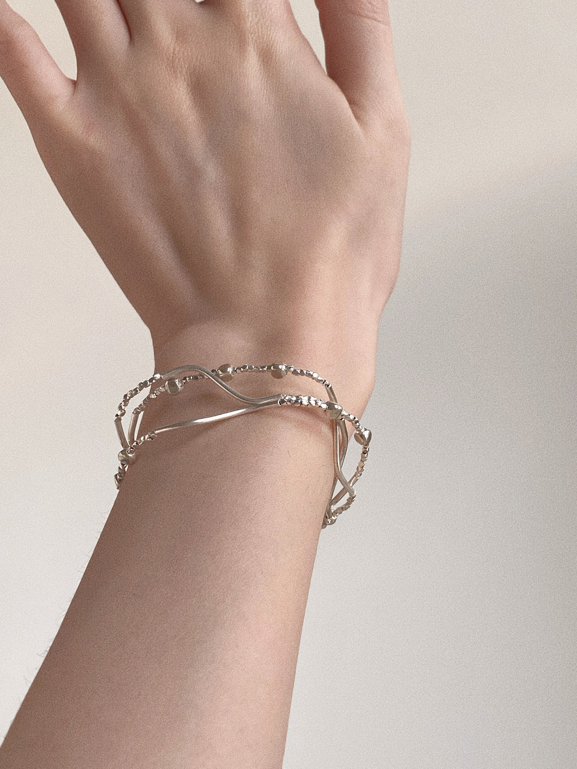 Dainty handmade triple-layer 925 sterling silver wave bracelet on woman's wrist for everyday styling