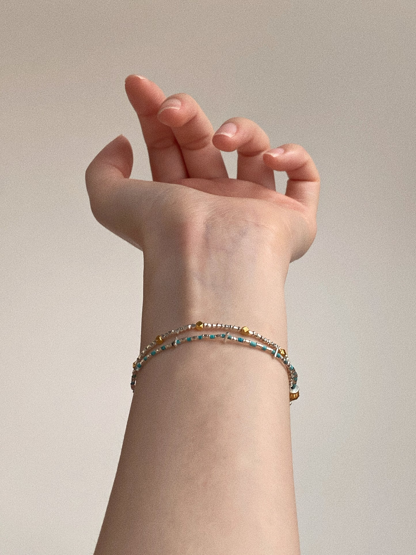 Dainty handmade turquoise and silver double-layer bracelet styled on slim wrist for everyday wear